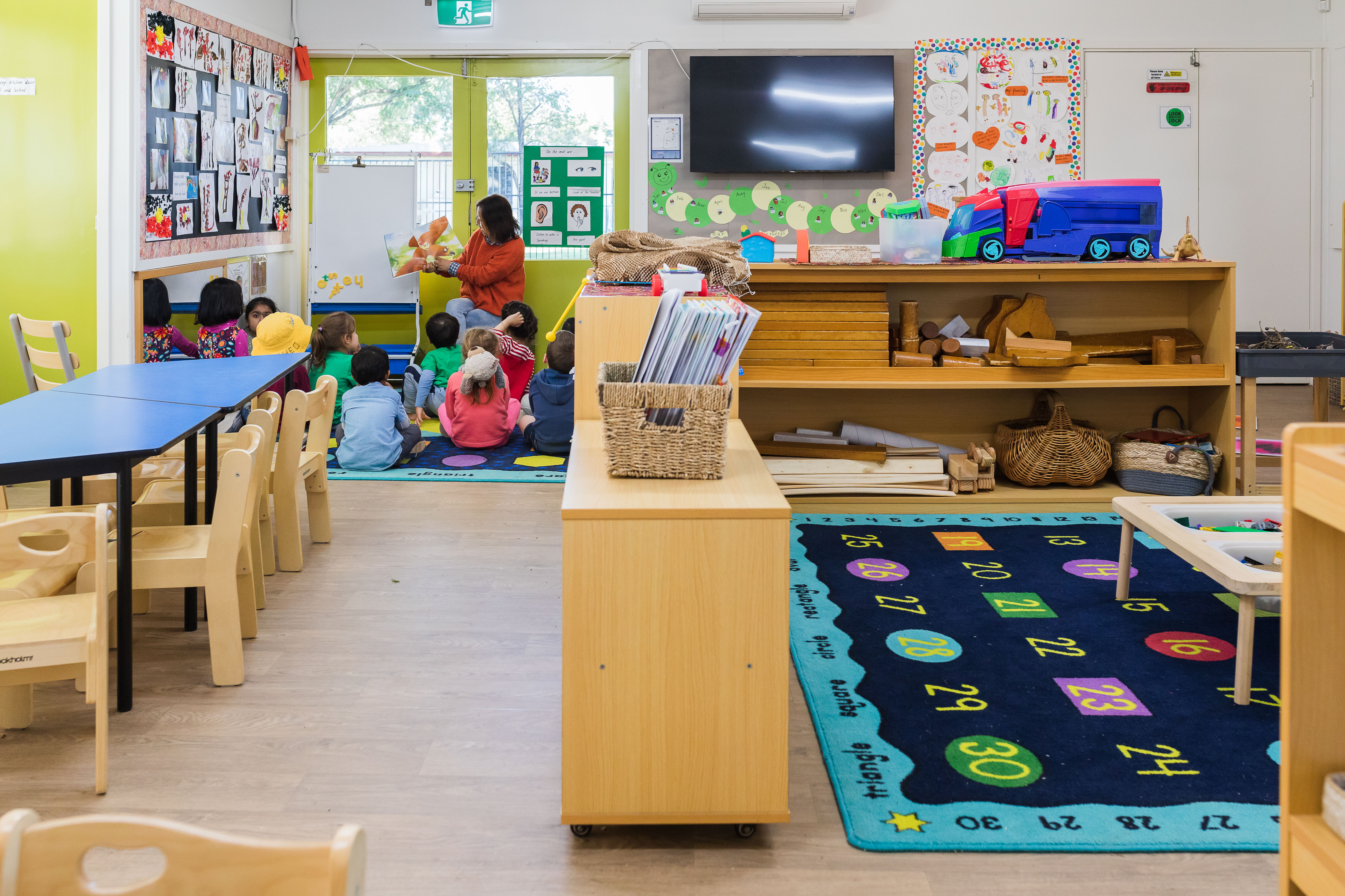Inside kindy, with educator reading children a book