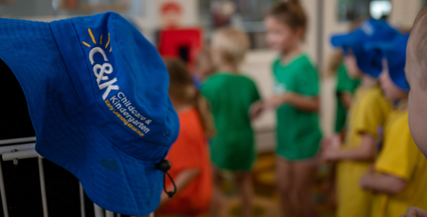 Branded C&K hat hanging with children in background