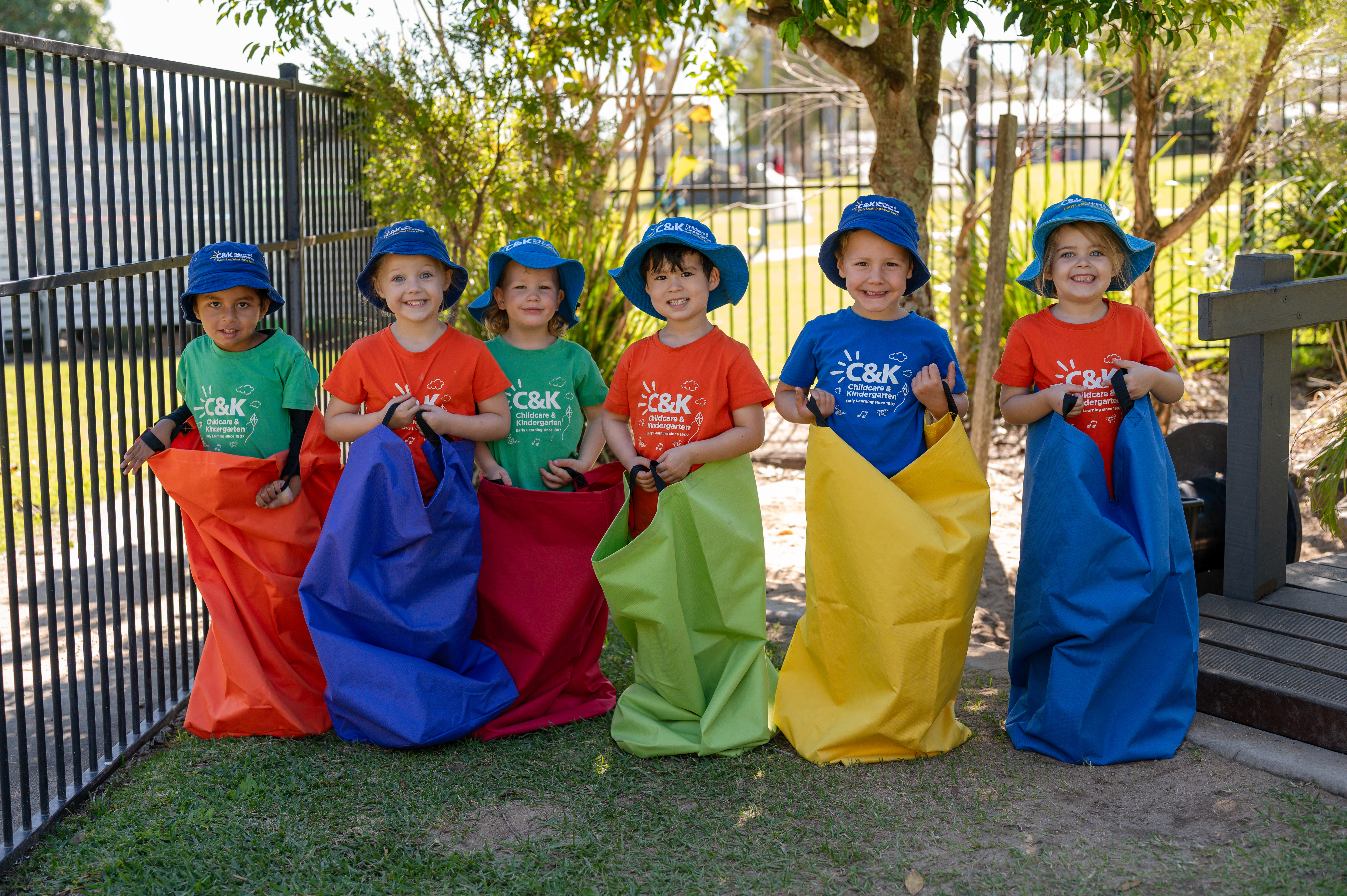 6 children in sacks outside smiling at camera