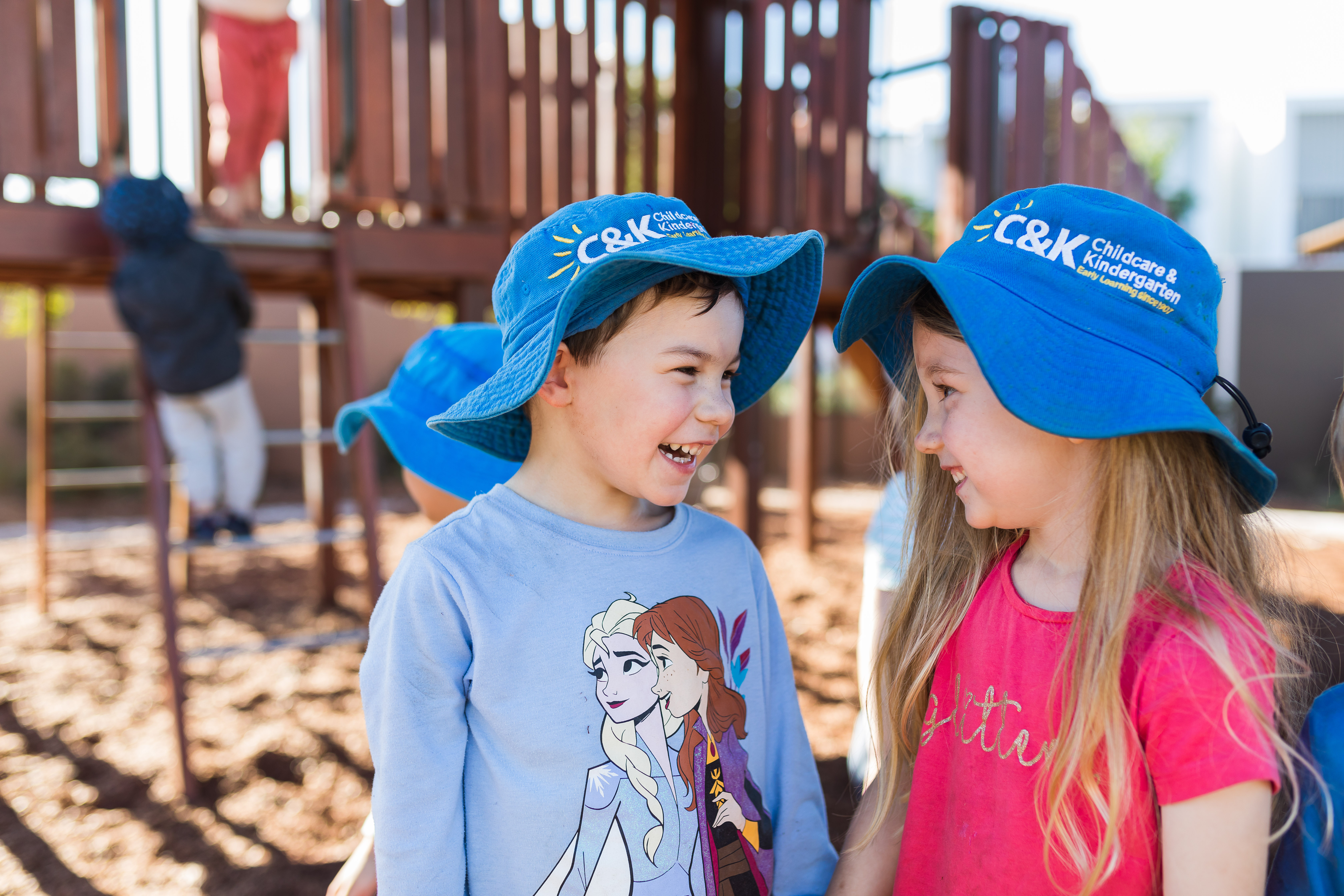 two children looking at each other smiling outside