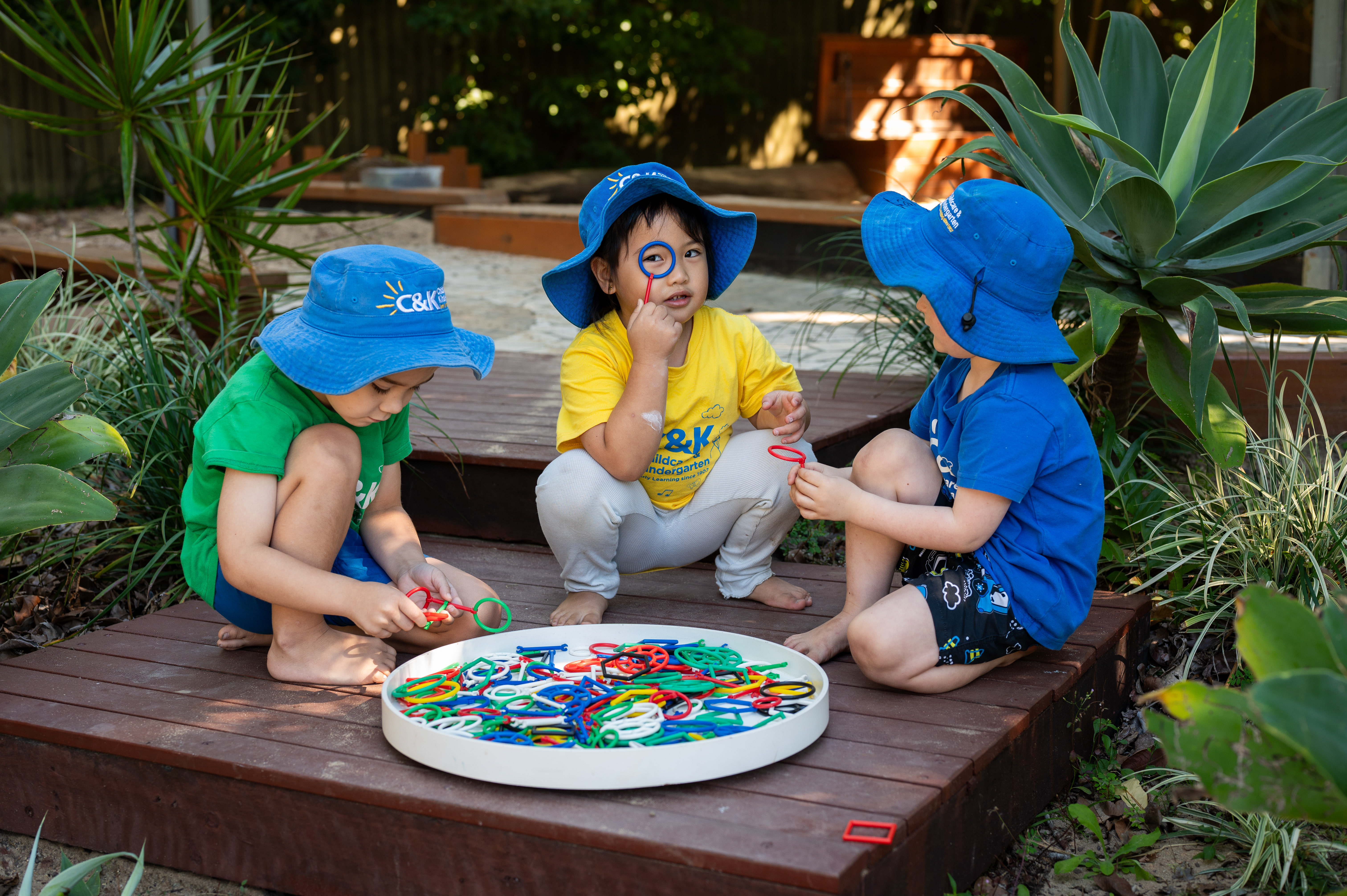 3 children doing an activity outside in shade