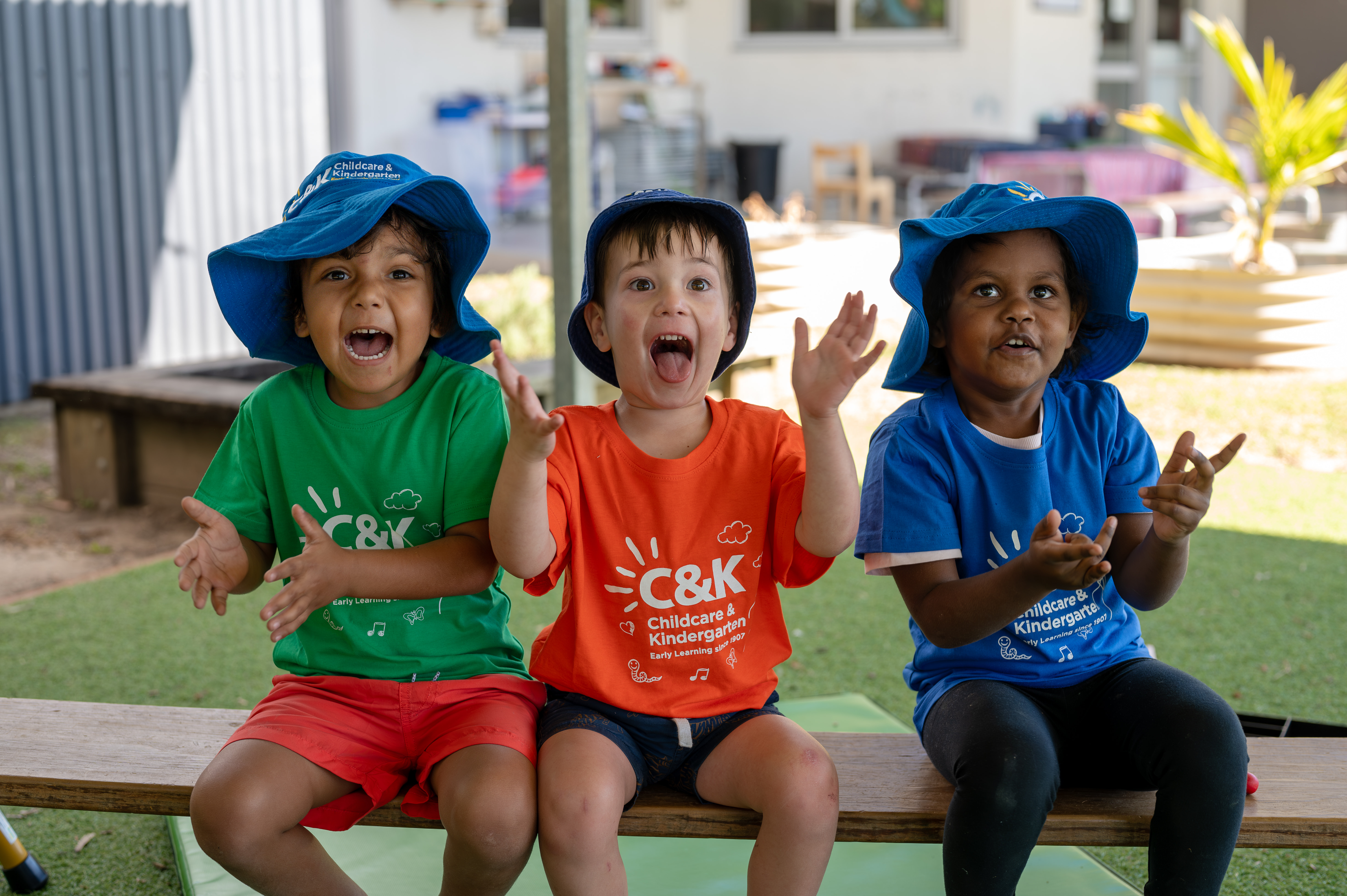 Three children playing outside smiling