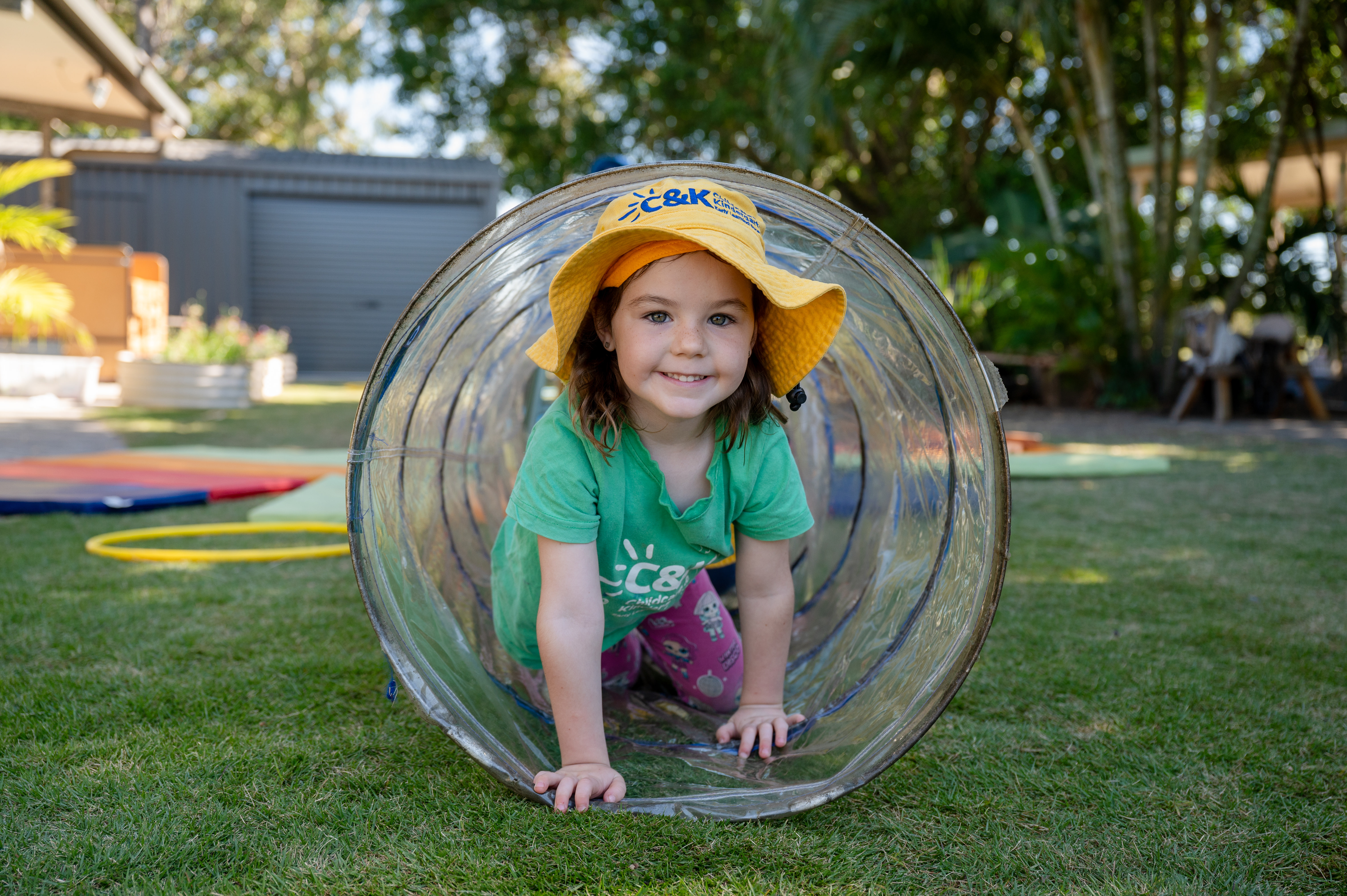 Girl outside crawling through tube smiling