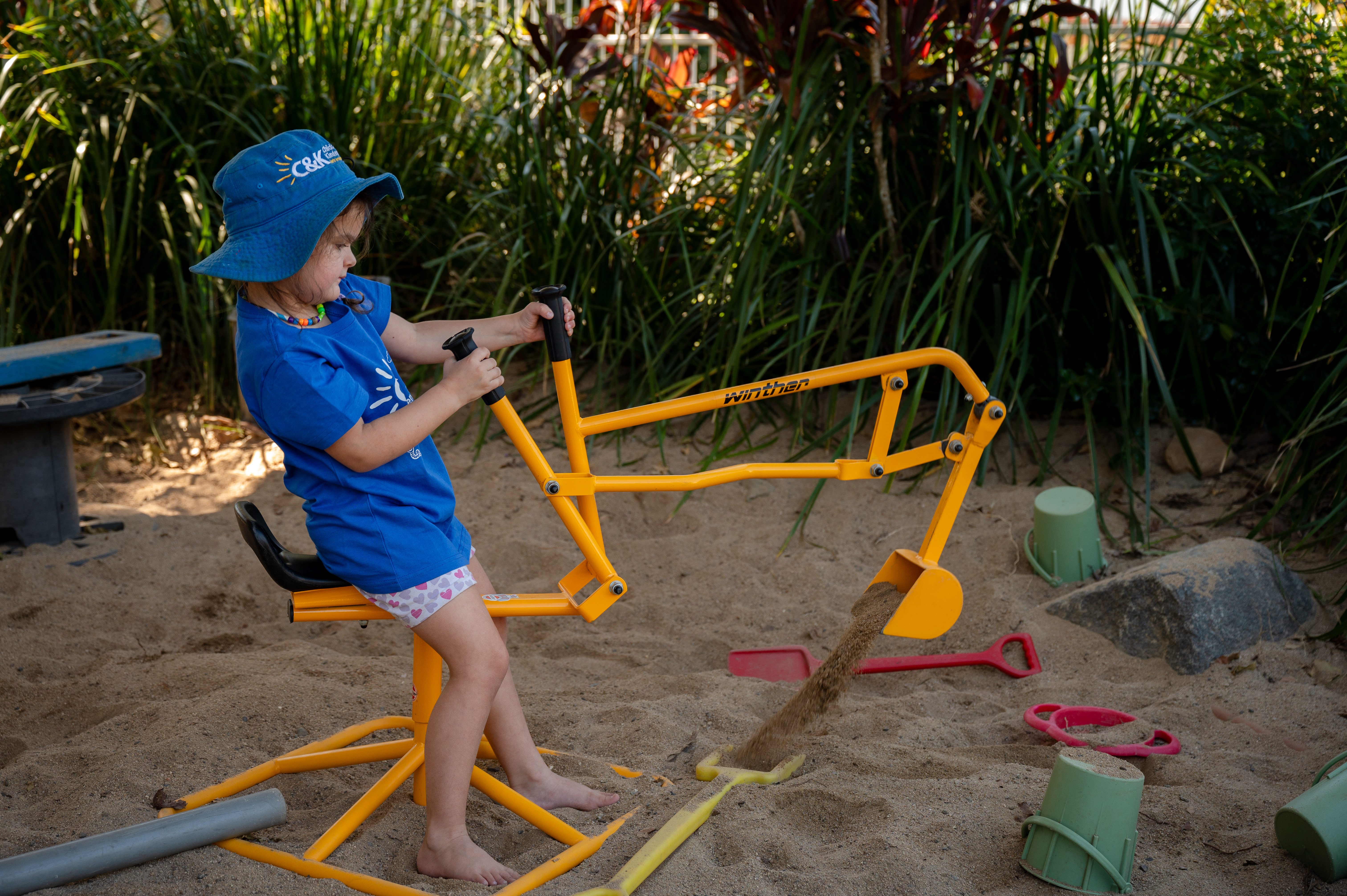 child playing with digger in sandpit