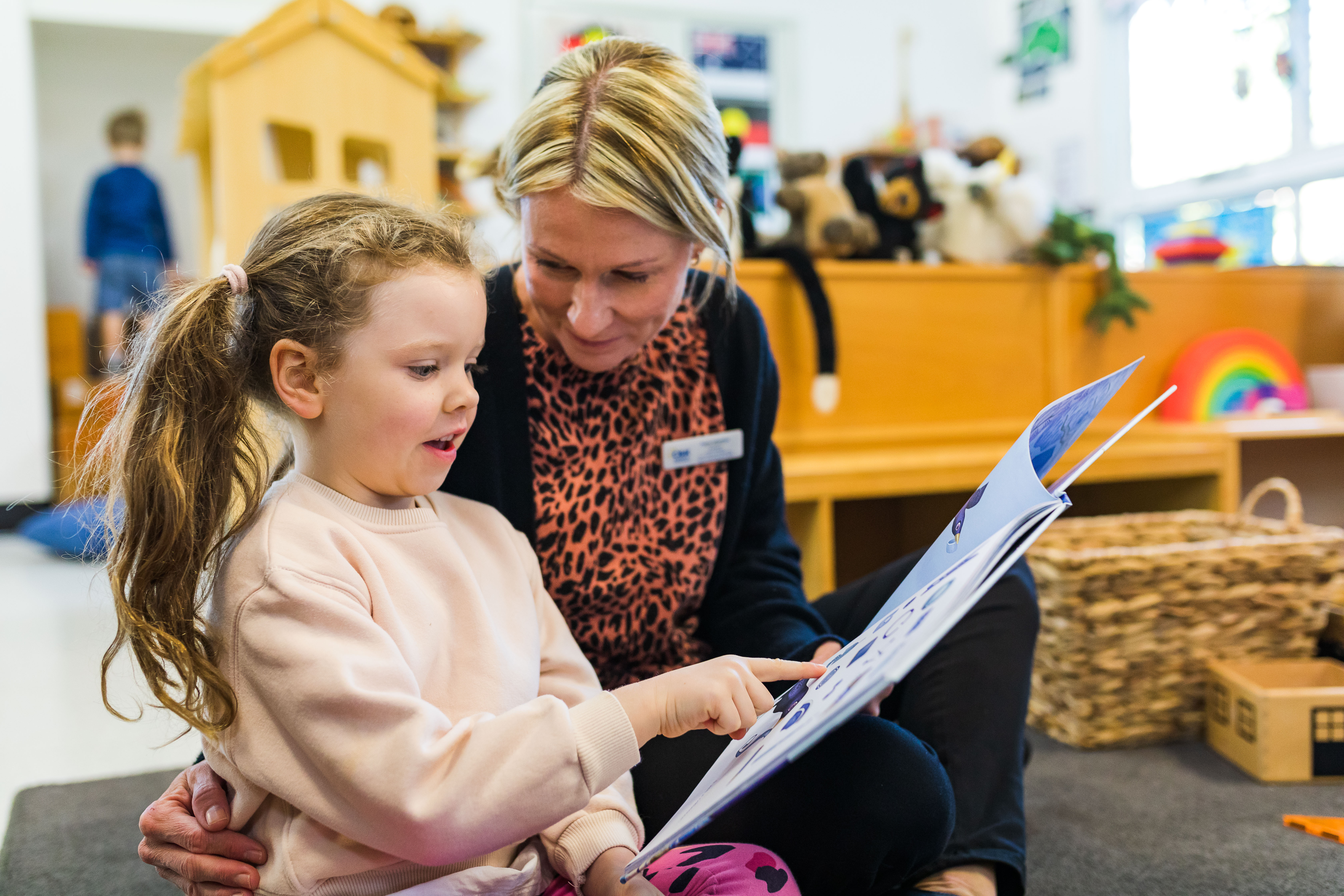 child and educator reading a book inside