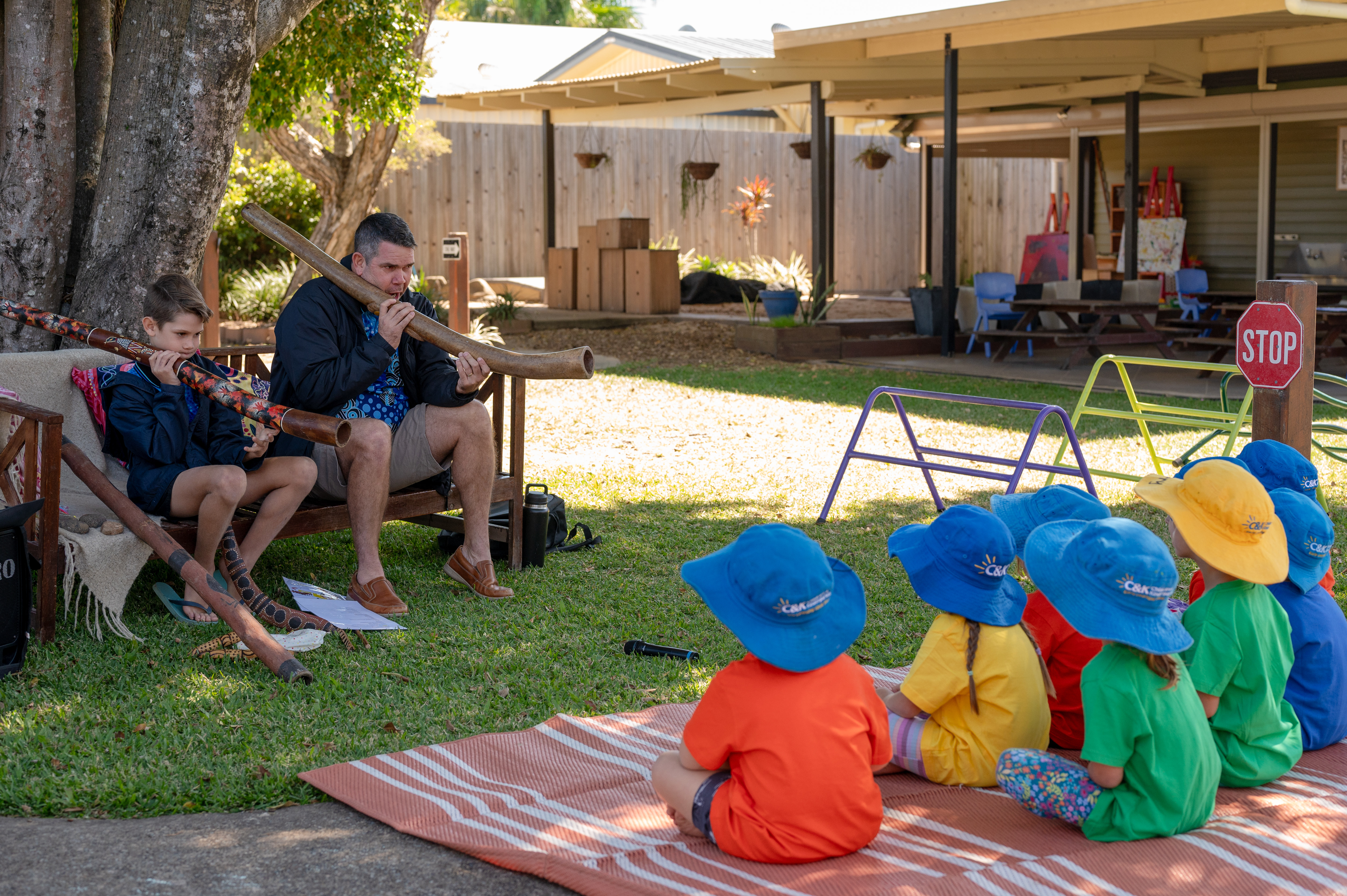 Elder playing digeridoo to children outside