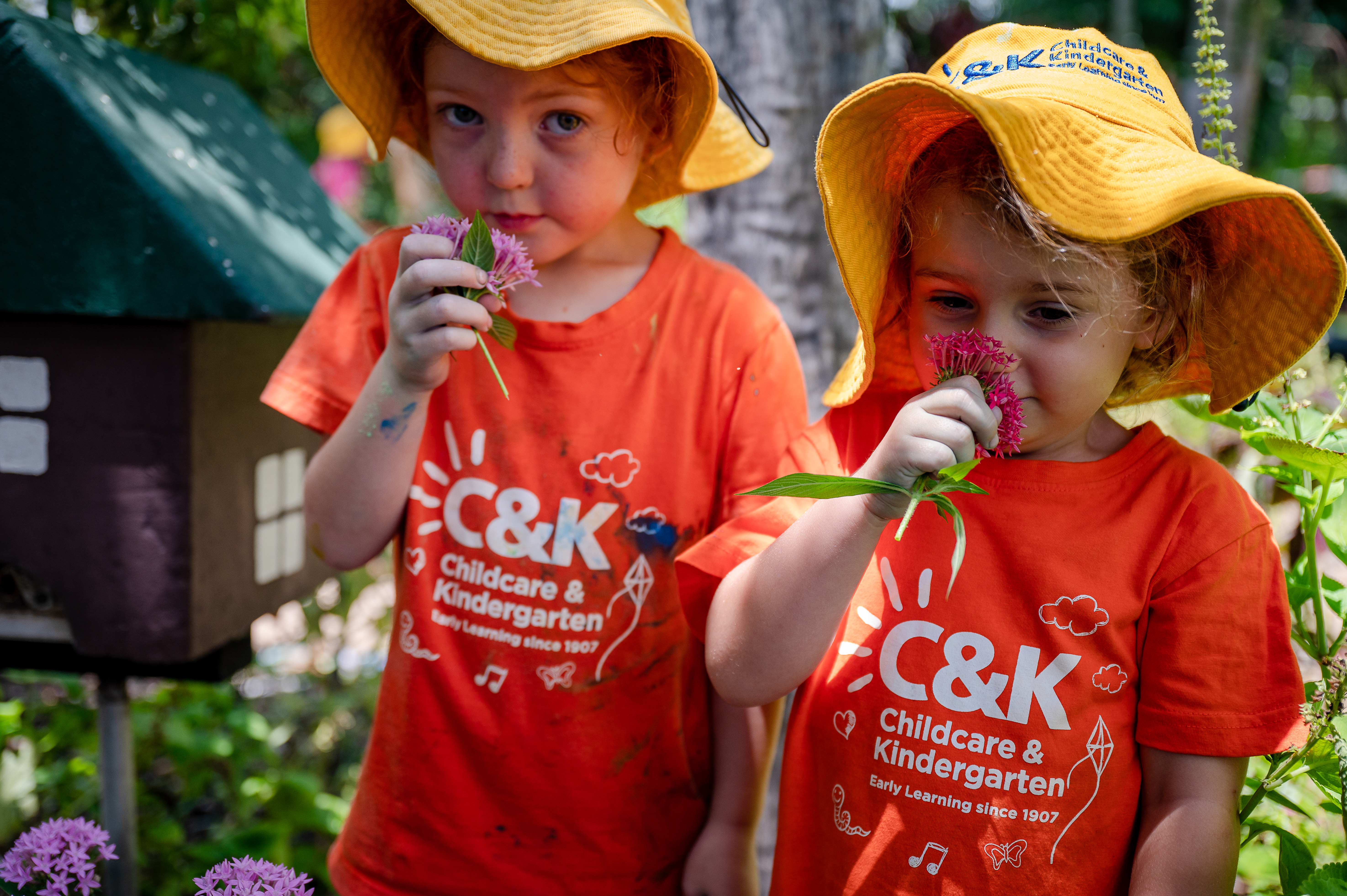 Two children outside smelling flowers