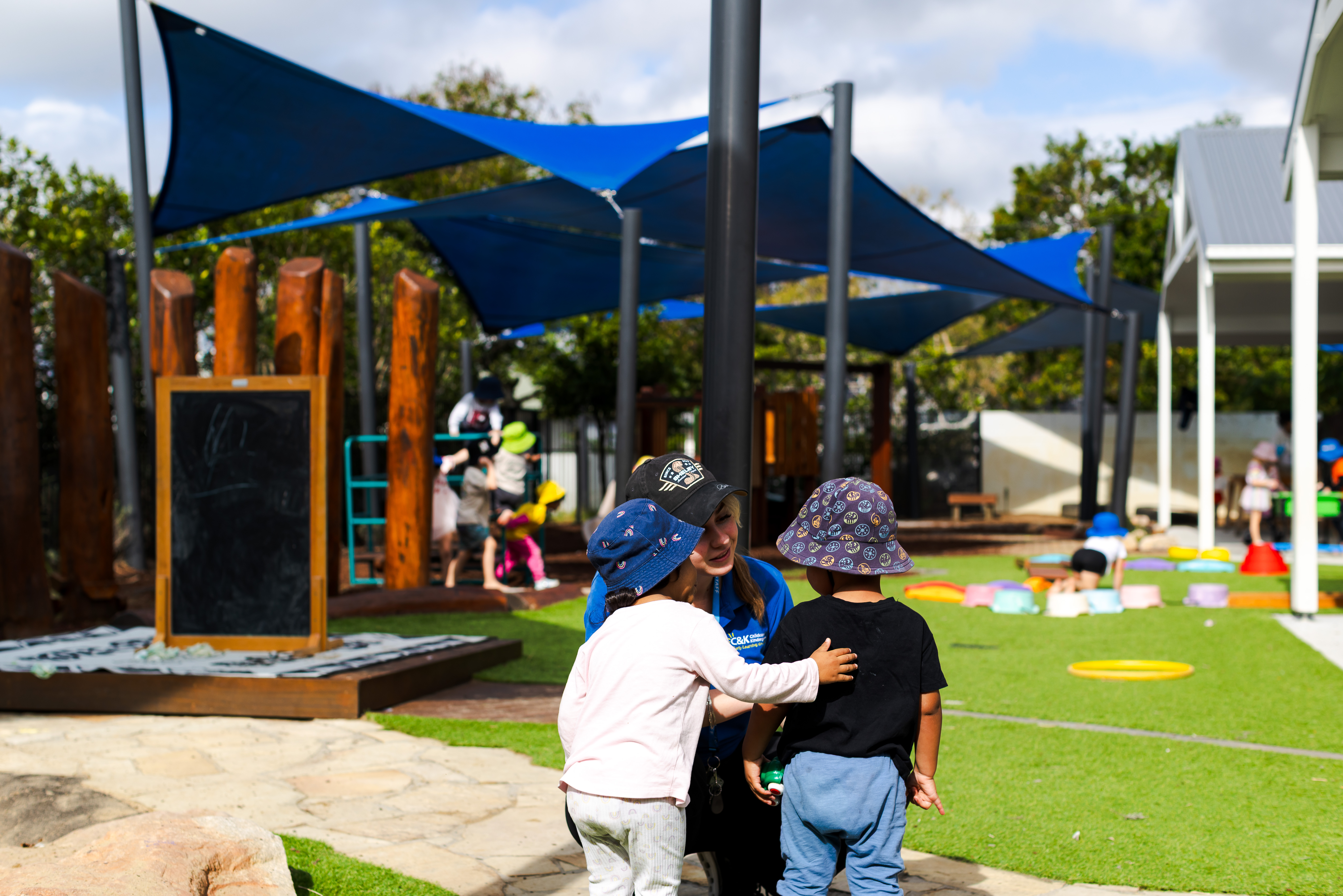 One kindy child with their hand on a friends back outside