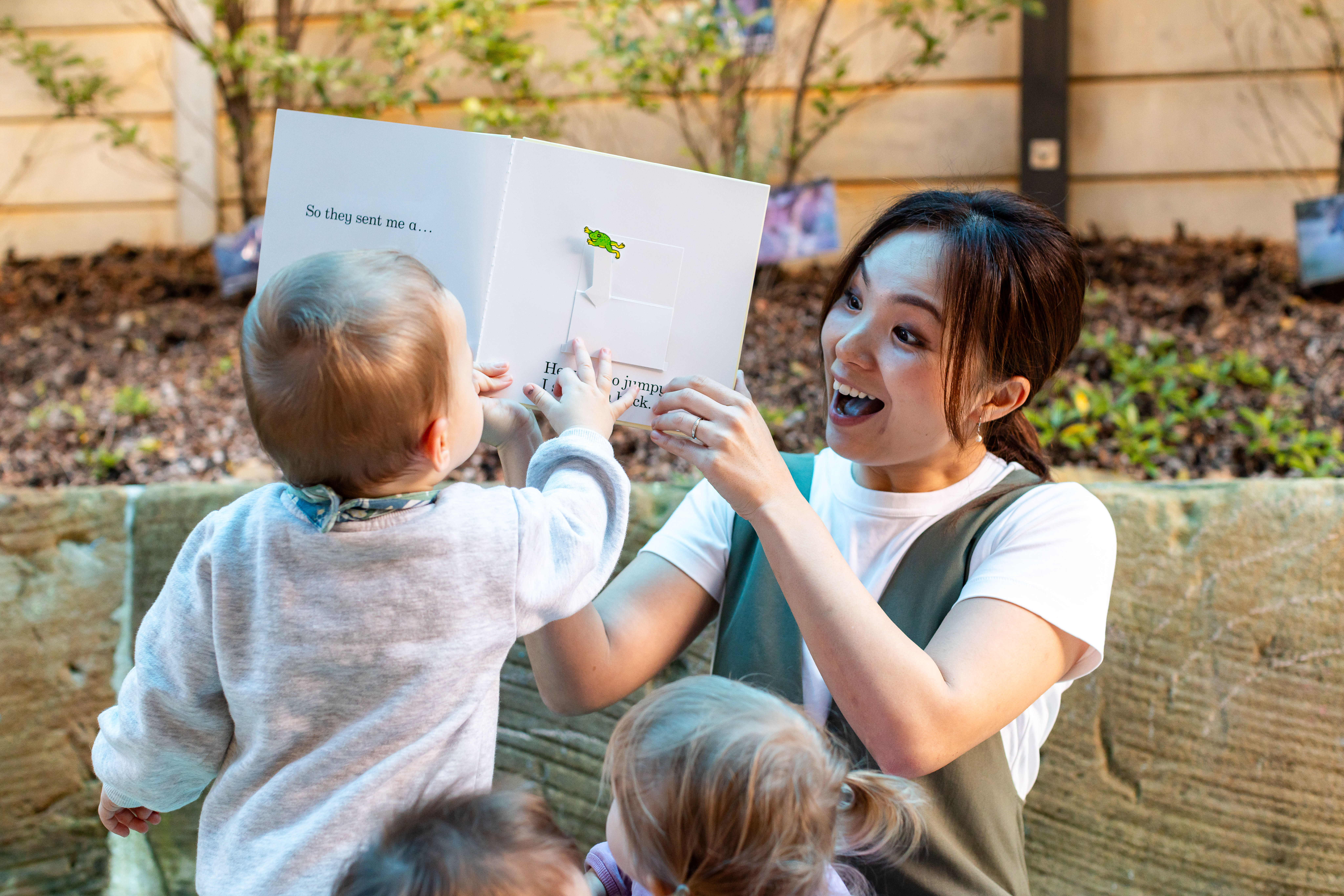 Educator smiling while reading to young toddlers