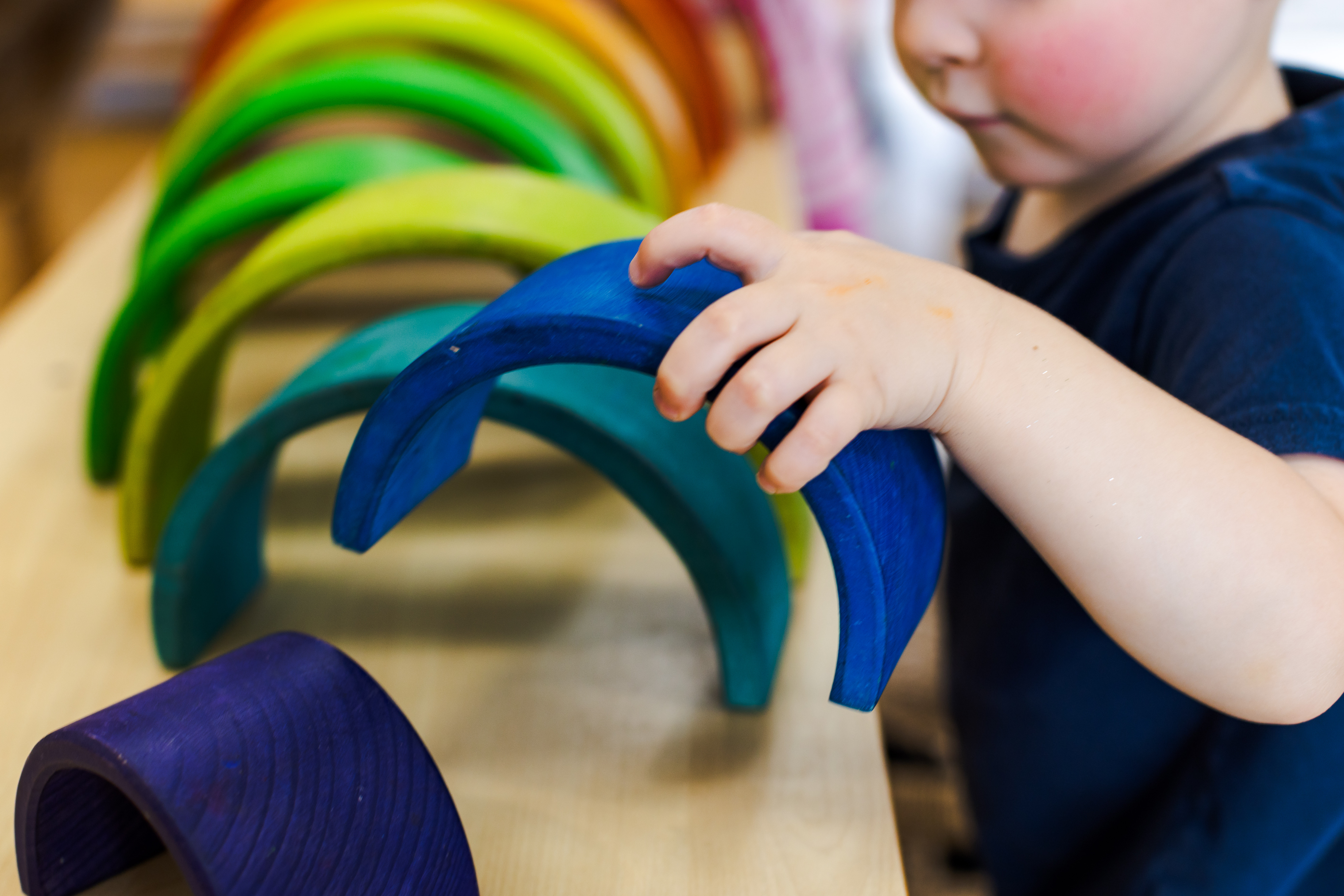 Toddler playing with wooden rainbow