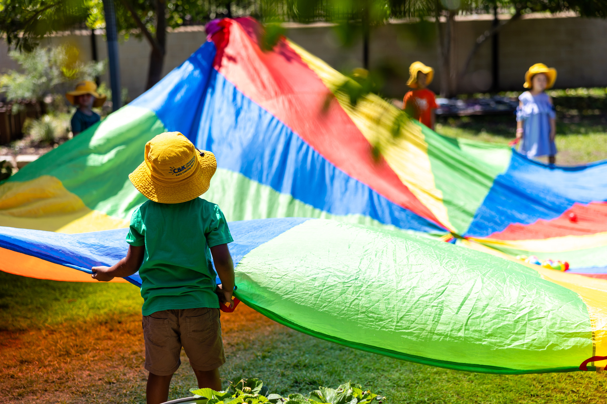 Children playing with a large, colourful parachute outside