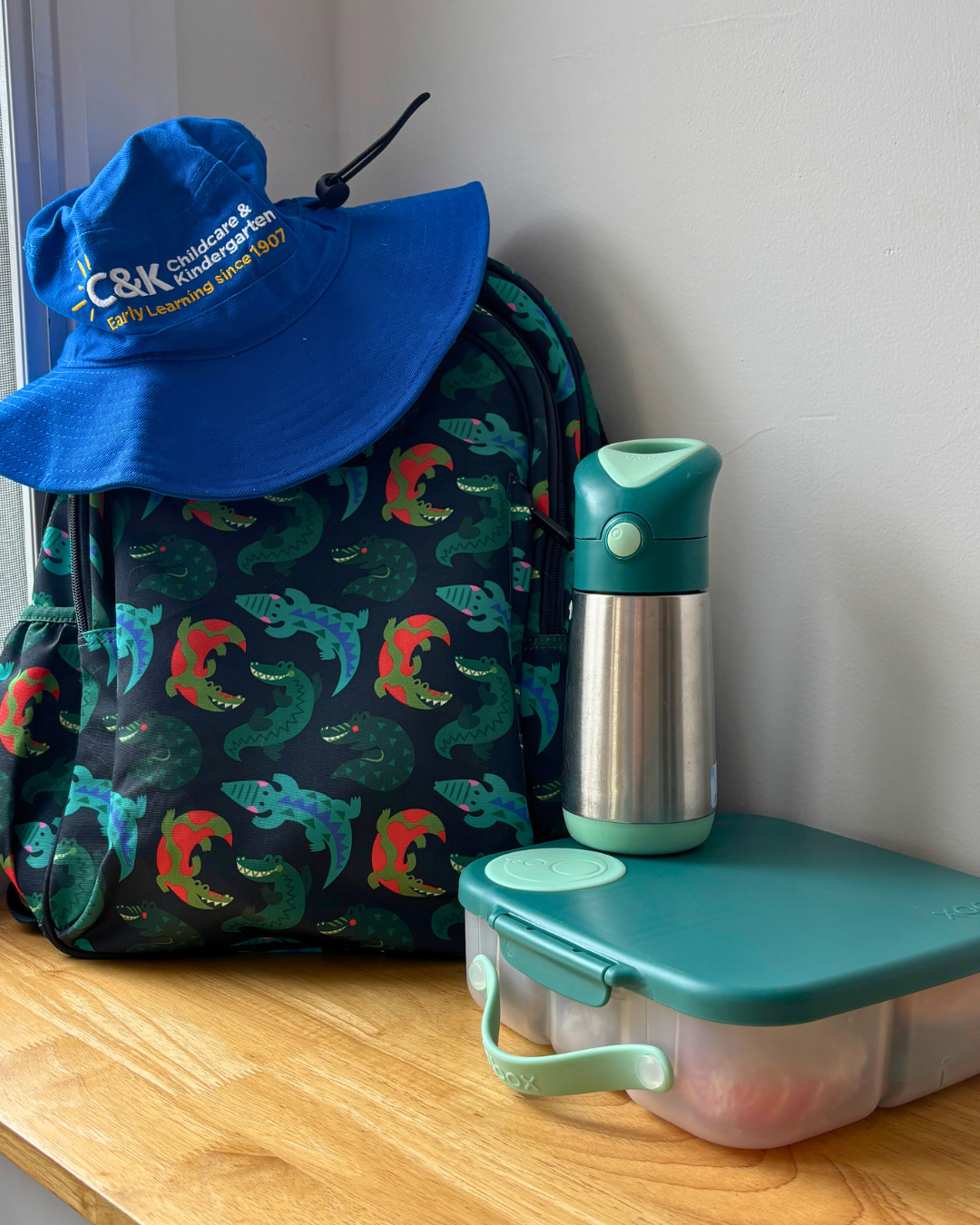 A photo of a backpack, water bottle, lunchbox, and C&K hat.