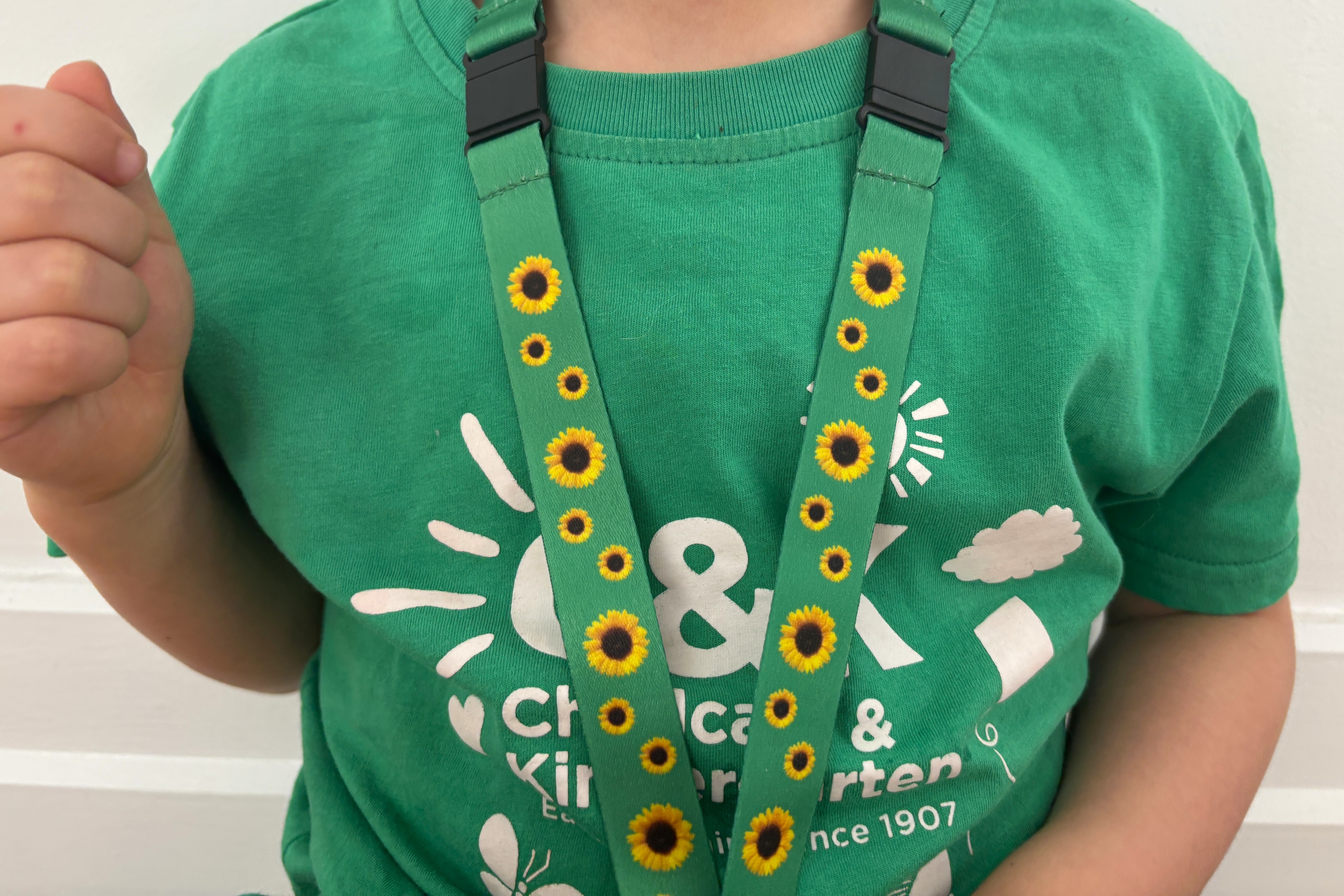 Child in a C&K shirt wearing a Hidden Disabilities sunflower lanyard