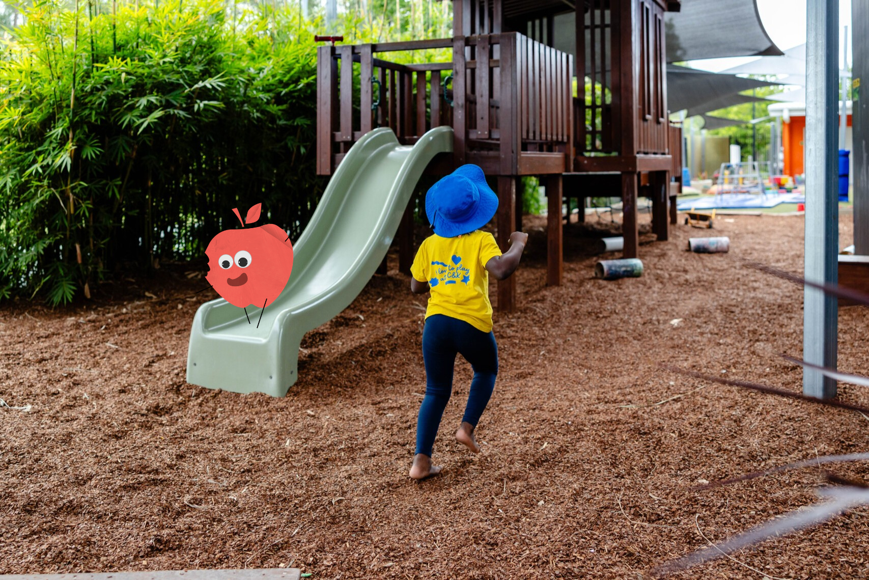 Girl running through a playground, the Apple Papermate is at the bottom of the slide
