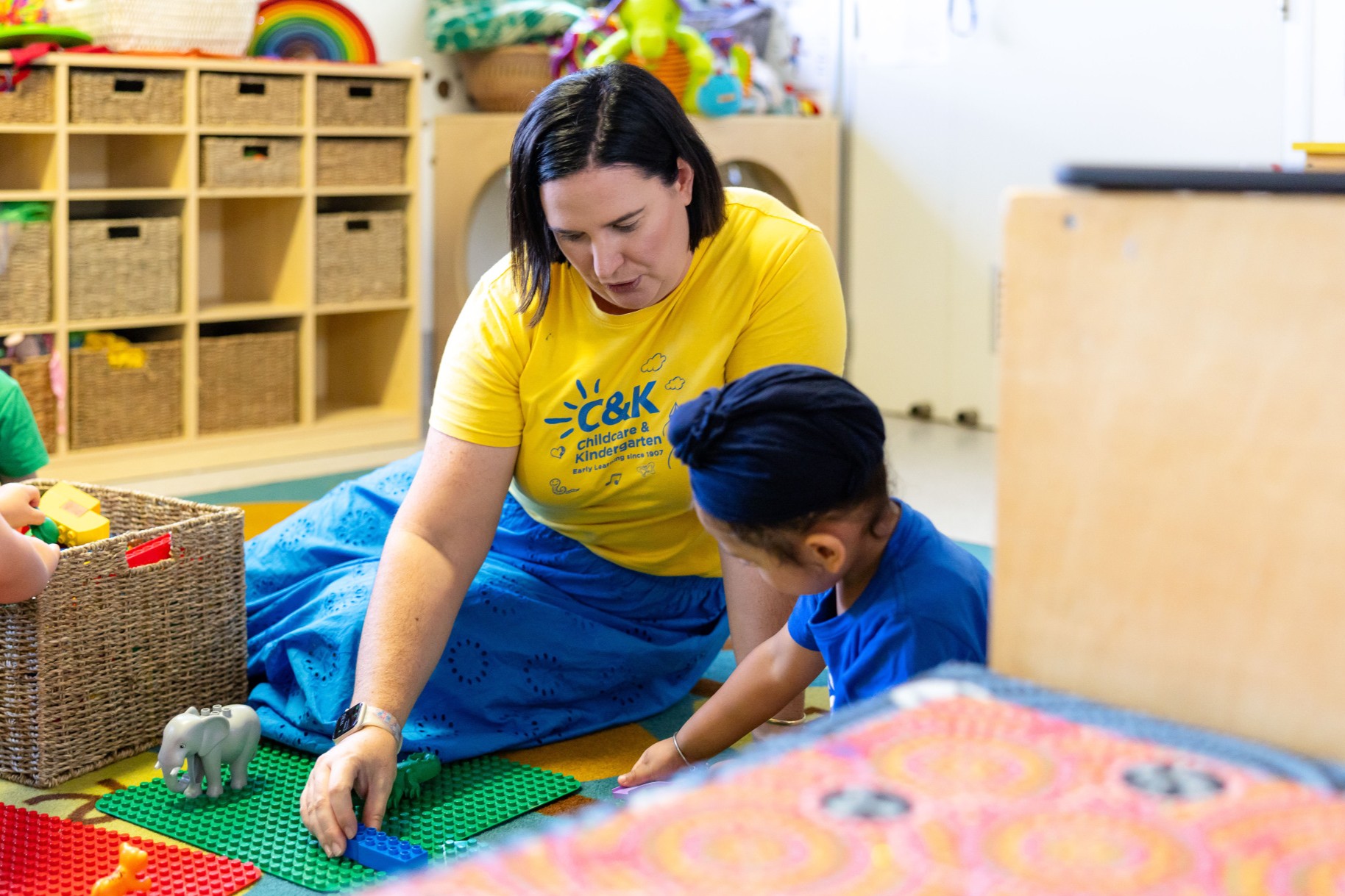 An educator working together with a child to build a Duplo creation