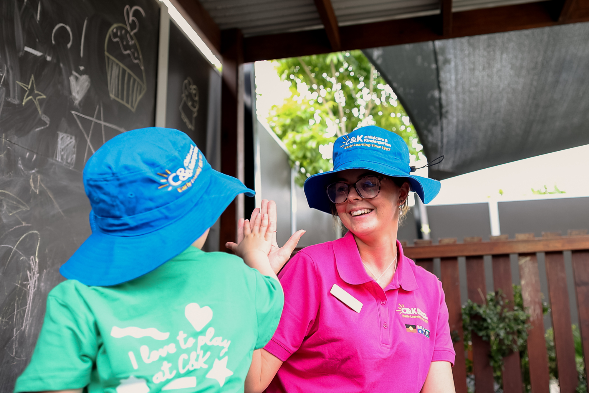 Educator smiling and high fiving toddler outside