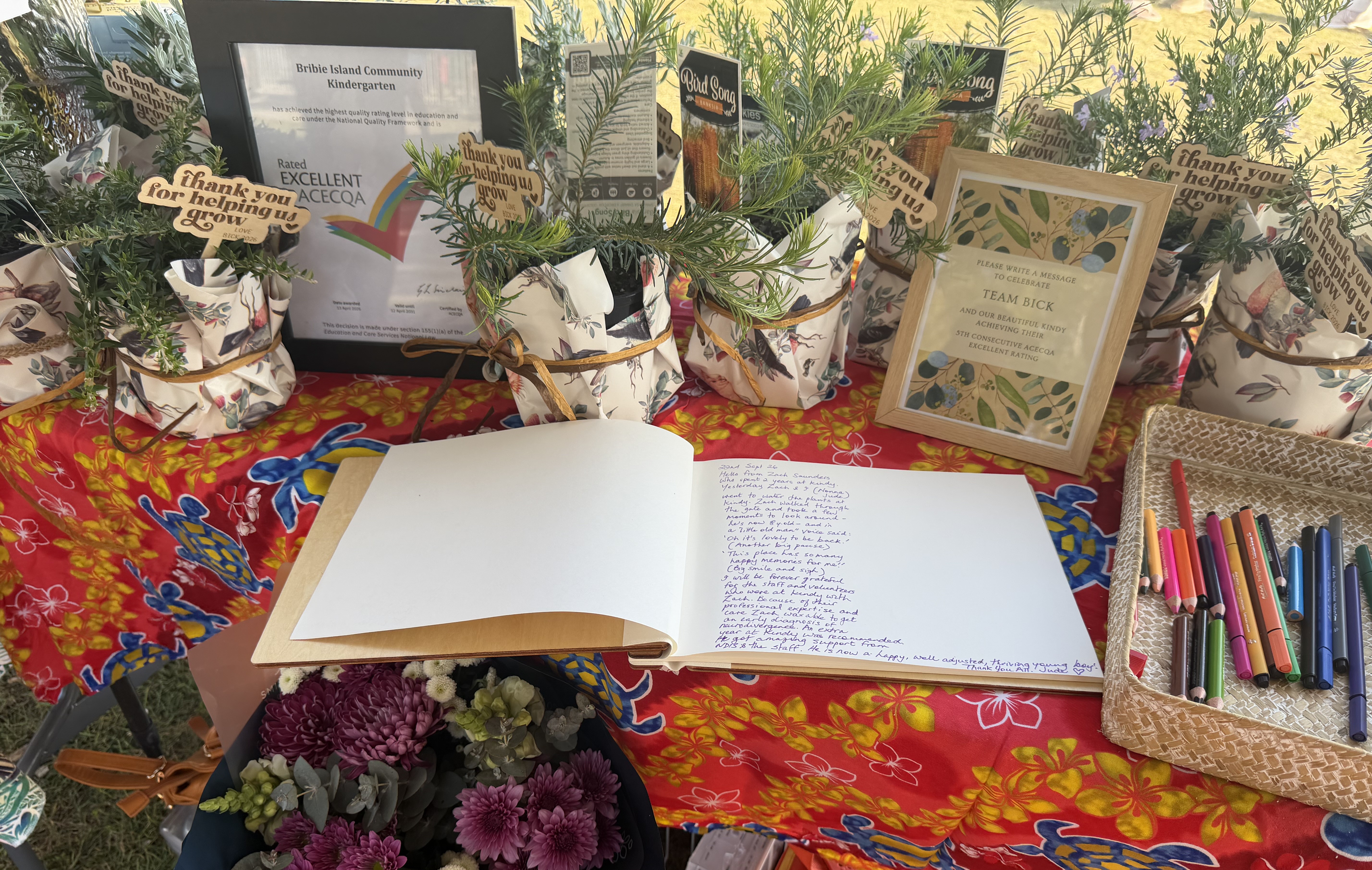 Excellent rating certificate on a table, surrounded by a book filled with congratulatory messages, and gifts.