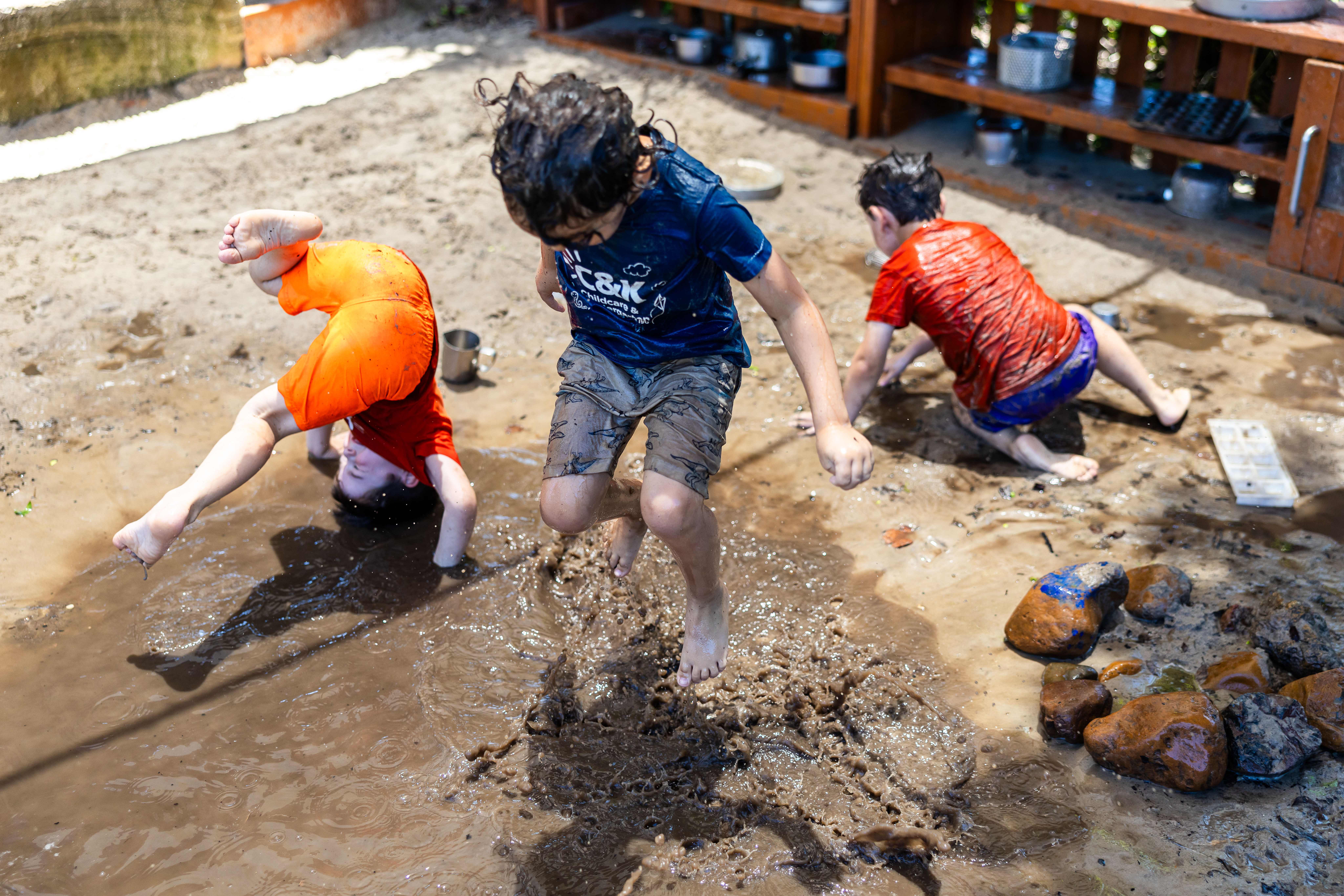 Children jumping and rolling in mud pit