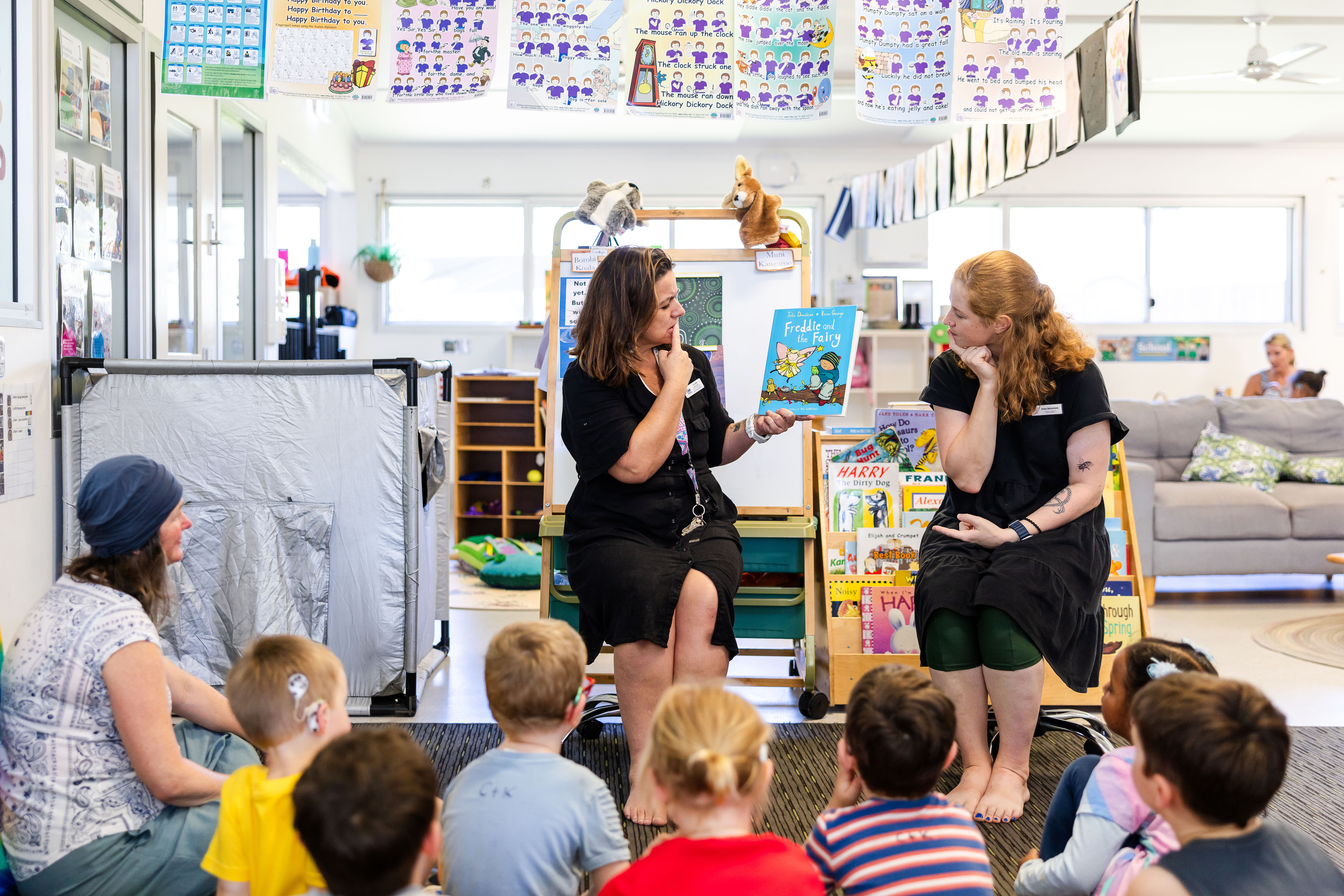 Teacher signing book to children on mat