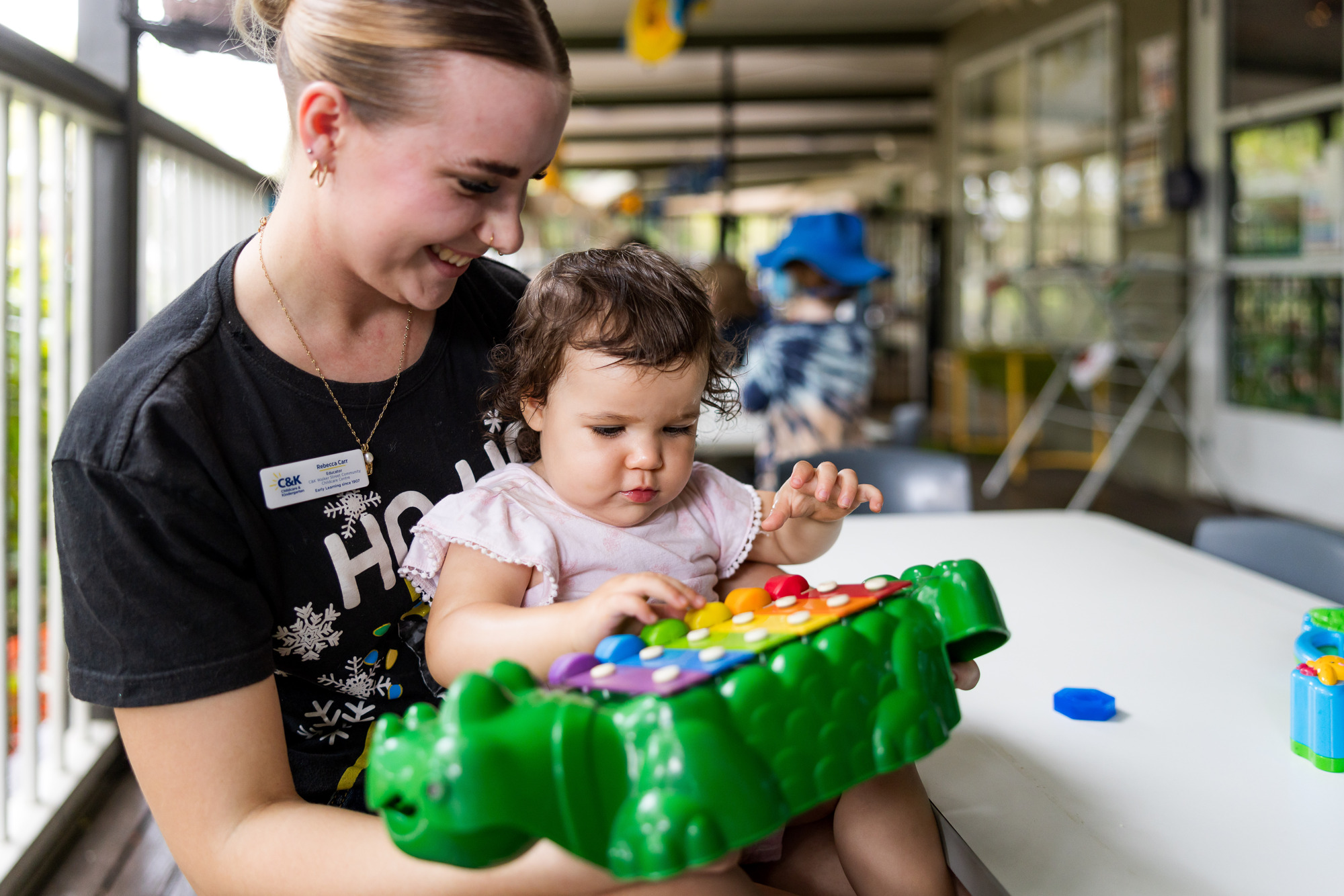Educator and baby playing with toy 