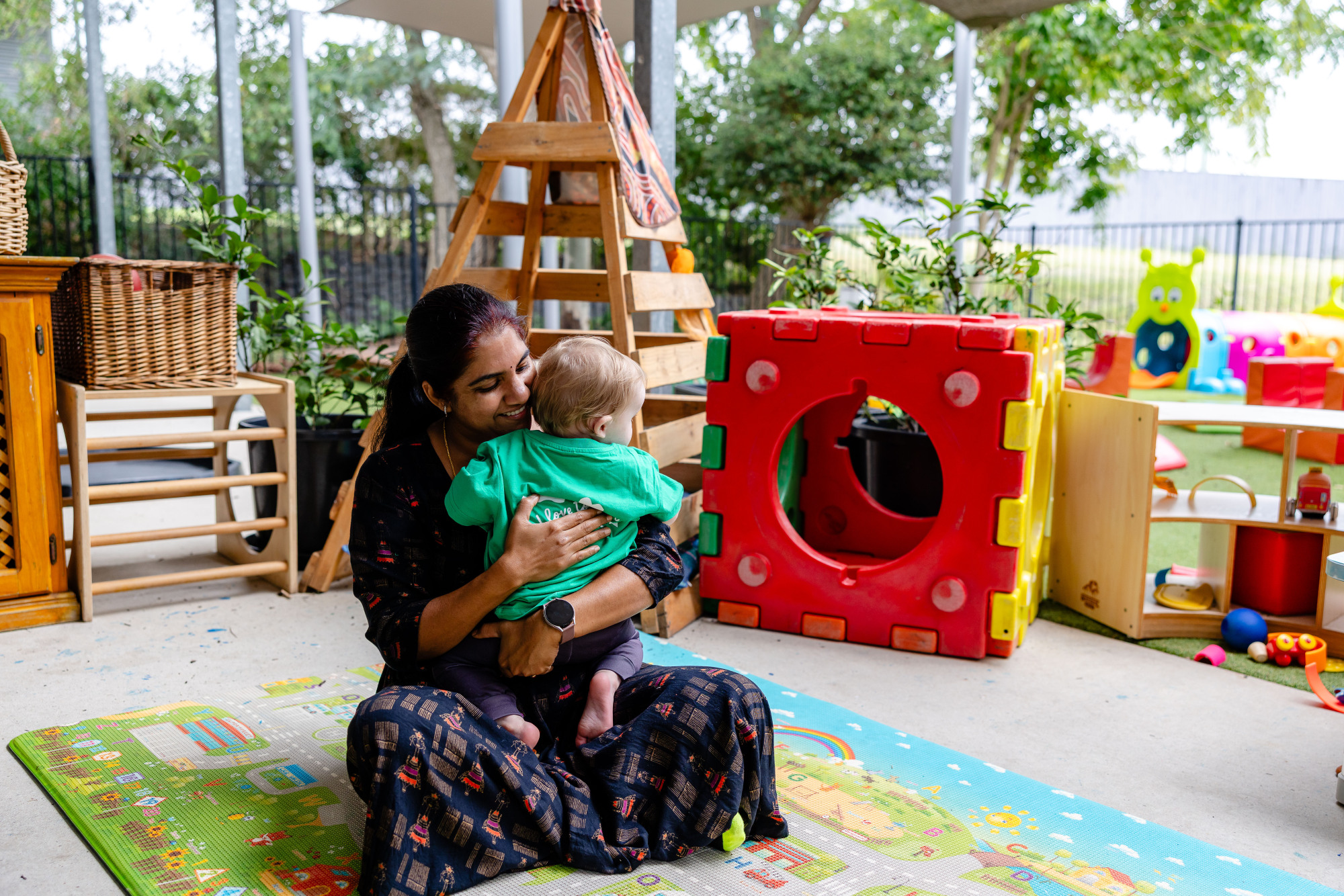 C&K Amberley - educator holding an infant, smiling