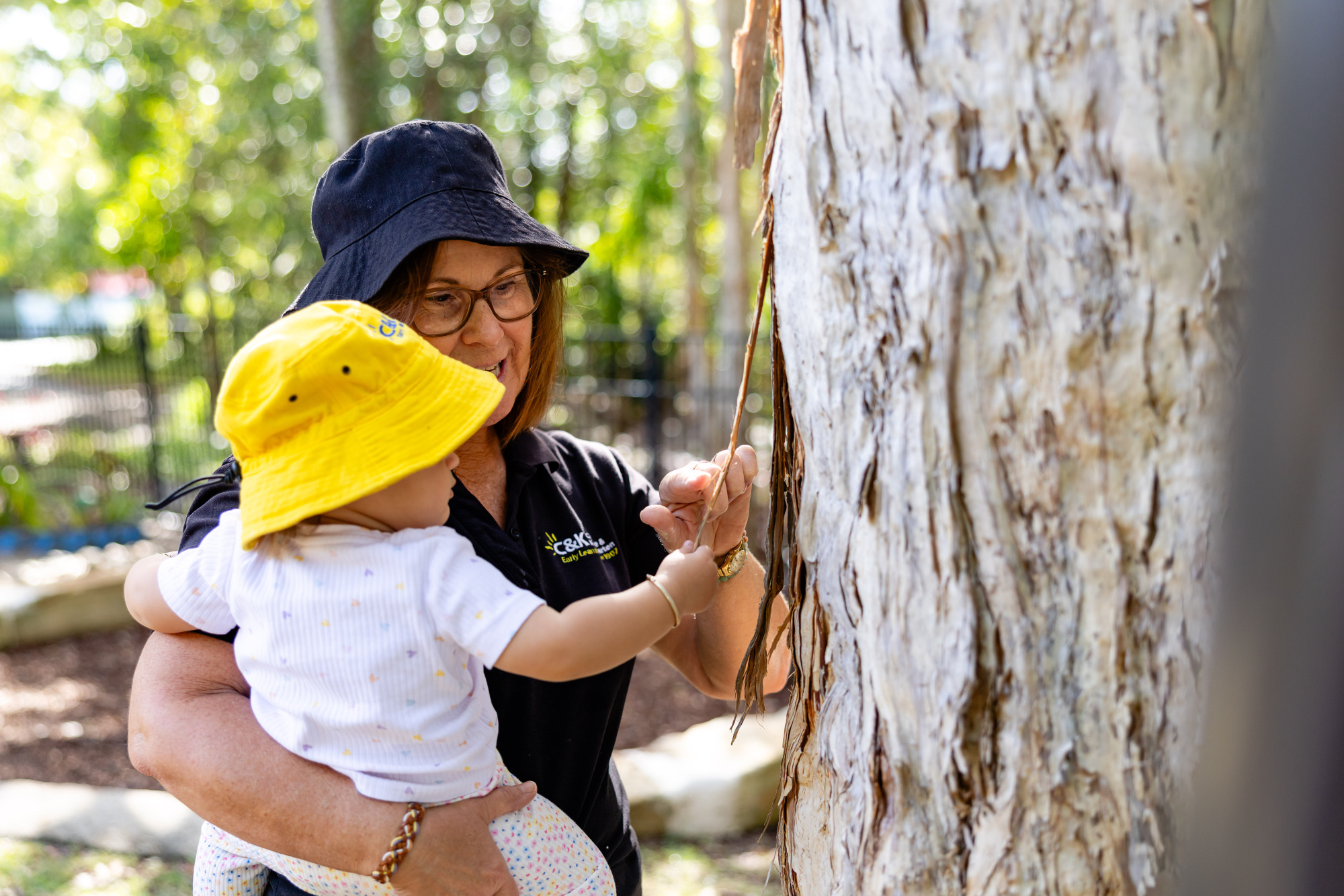 C&K Bradman Street - educator and infant feeling the bark on a tree
