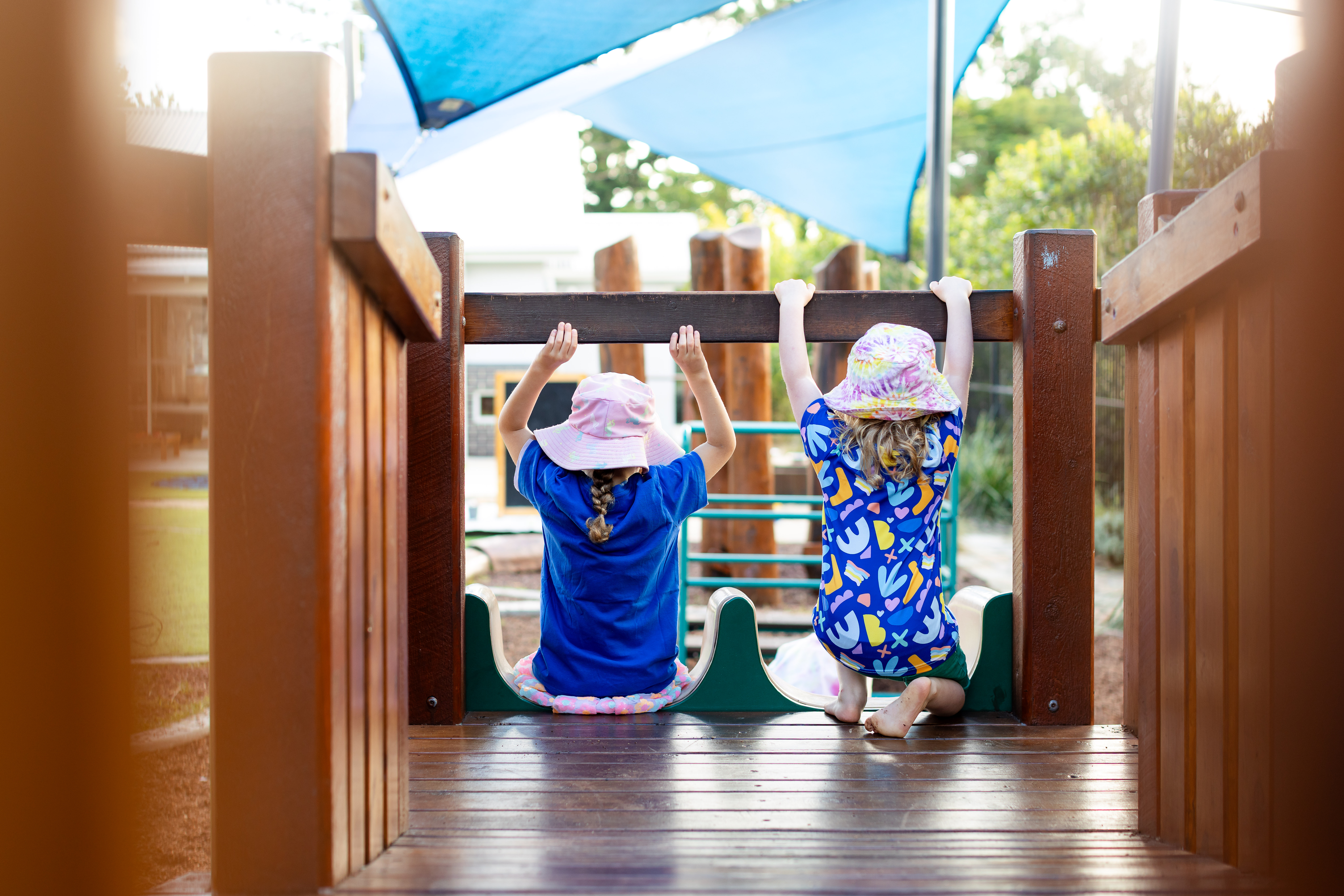 Two children sitting at the top of a slide