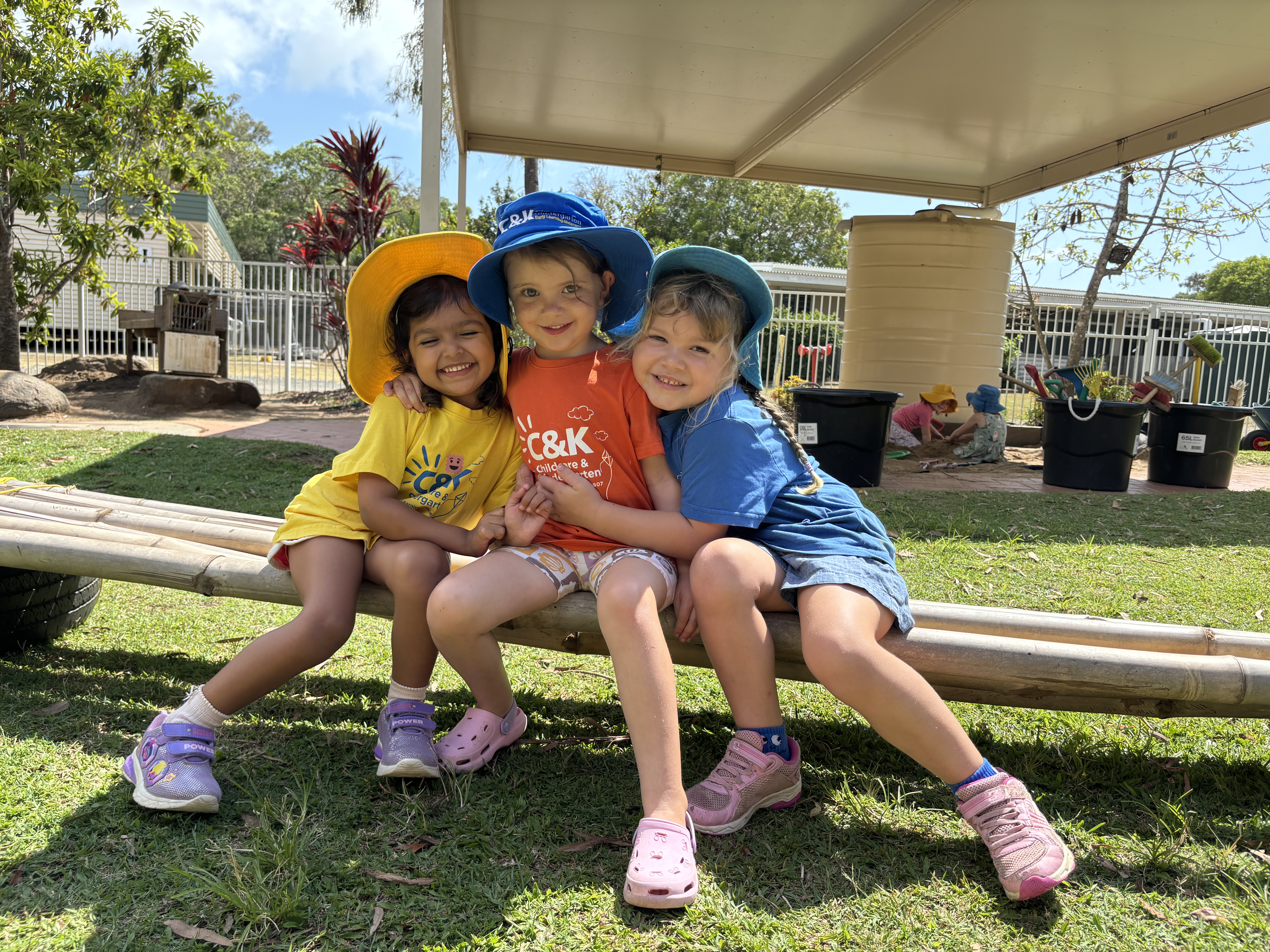 Three kindy friends smiling and hugging