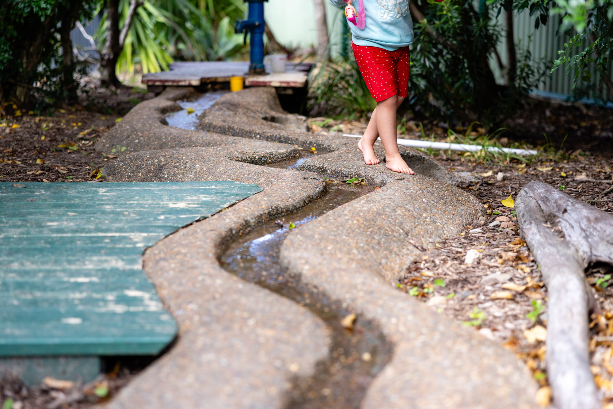 C&K Caboolture - child walking along a stream of water from the water pump