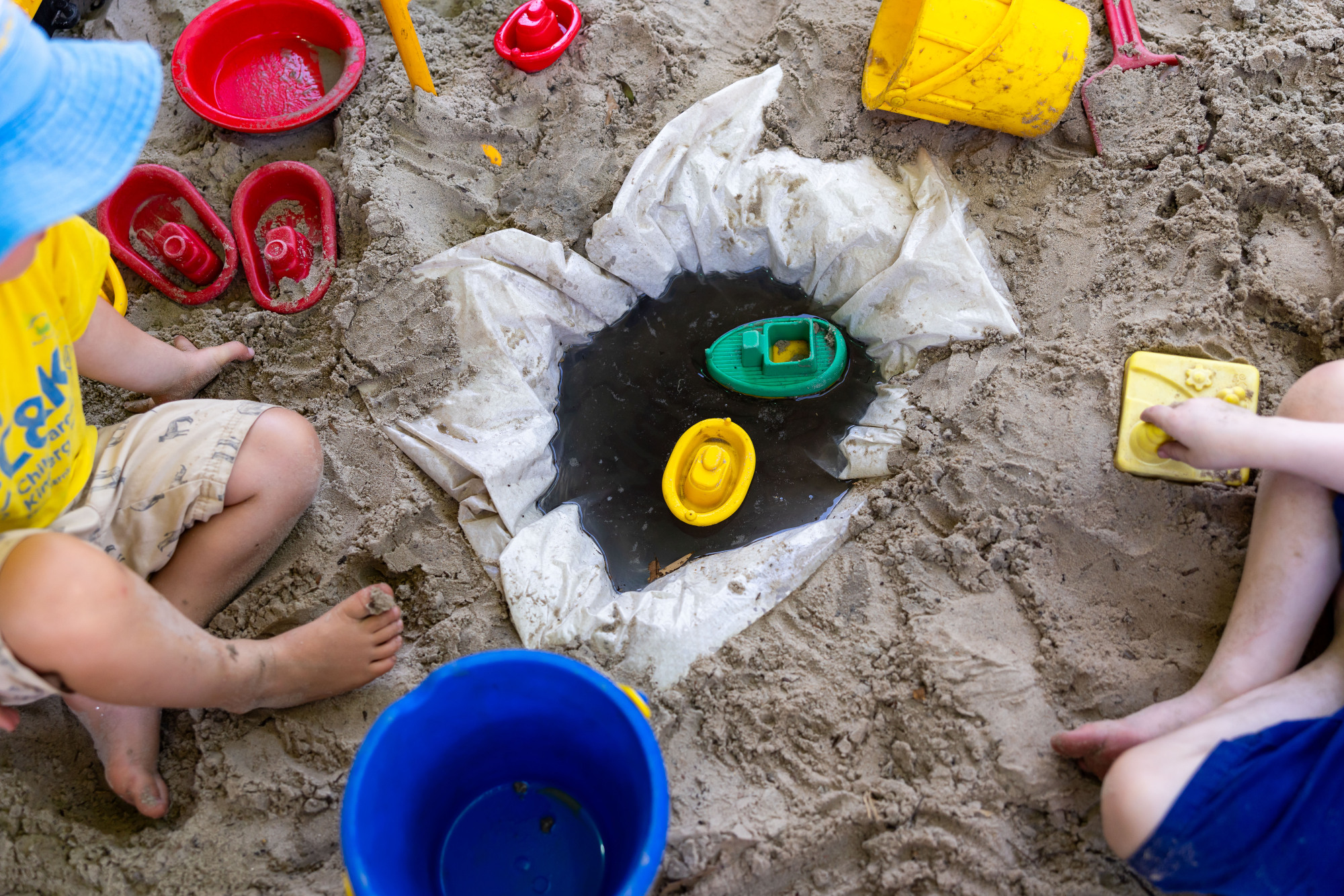 C&K Carindale - children floating boats in a small pool of water in the sandpit