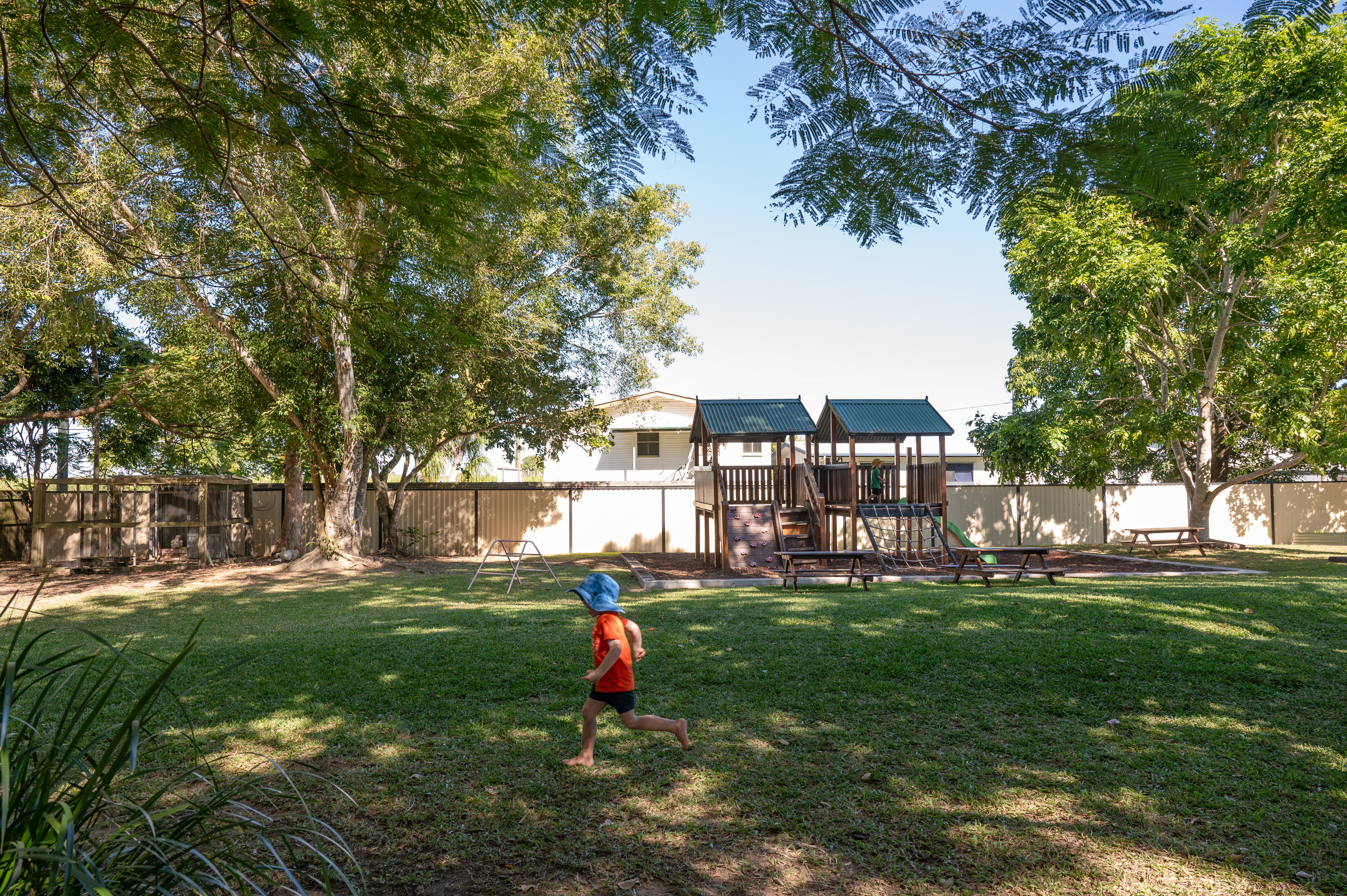 C&K Walkerston - child running across the large grassed outdoor space with the playground in the background