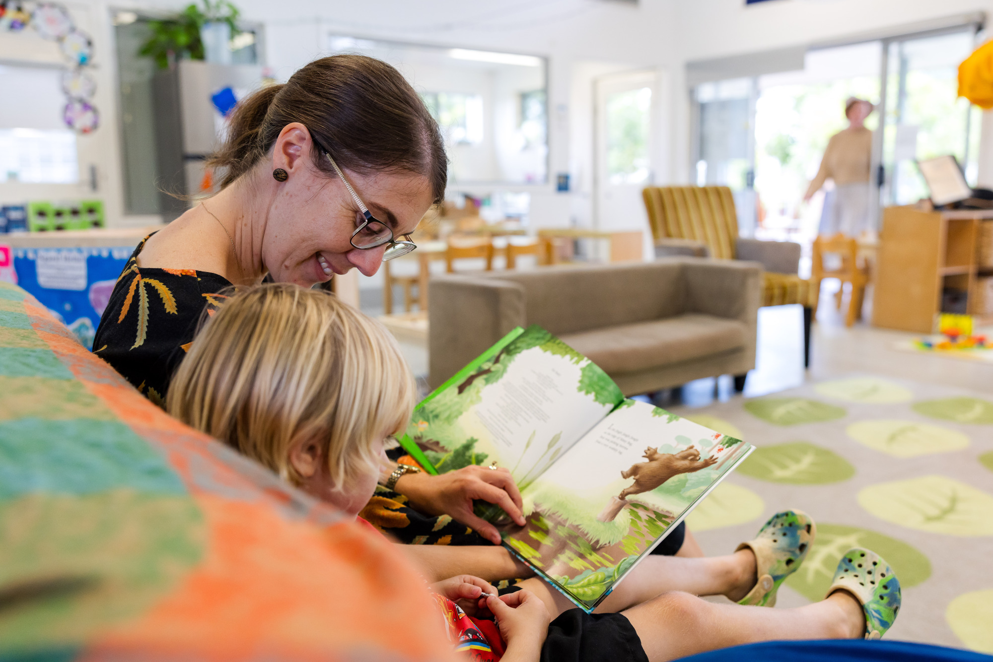 C&K Deception Bay North - teacher and child reading on a couch inside