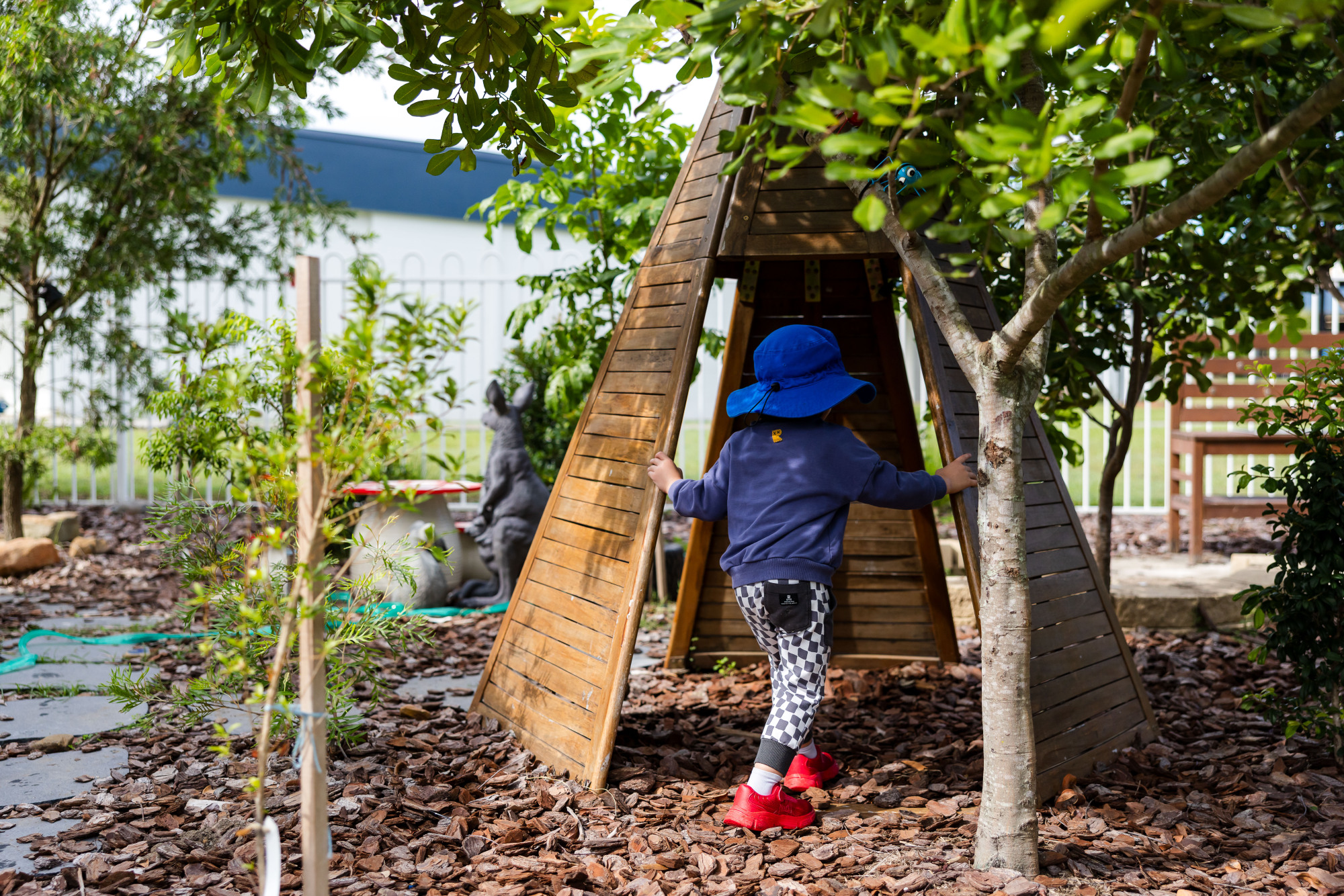 C&K Deception Bay North - child walking into a wooden teepee surrounded by trees