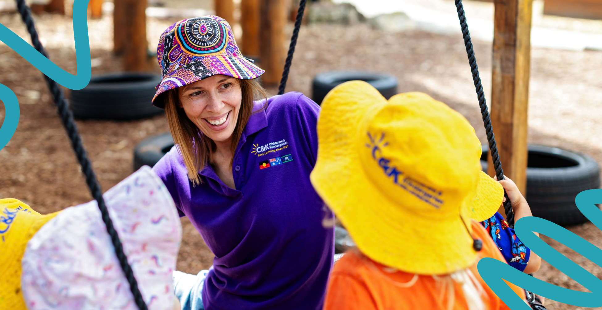 Educator sitting on a swing, smiling at children.