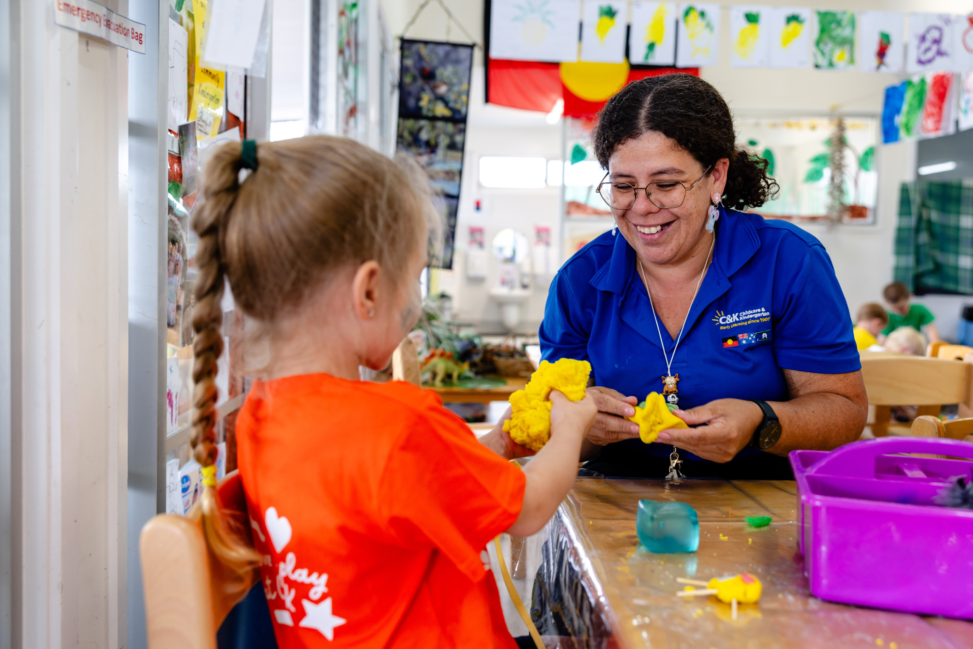 C&K Hatton Vale - smiling educator and child playing with playdoh