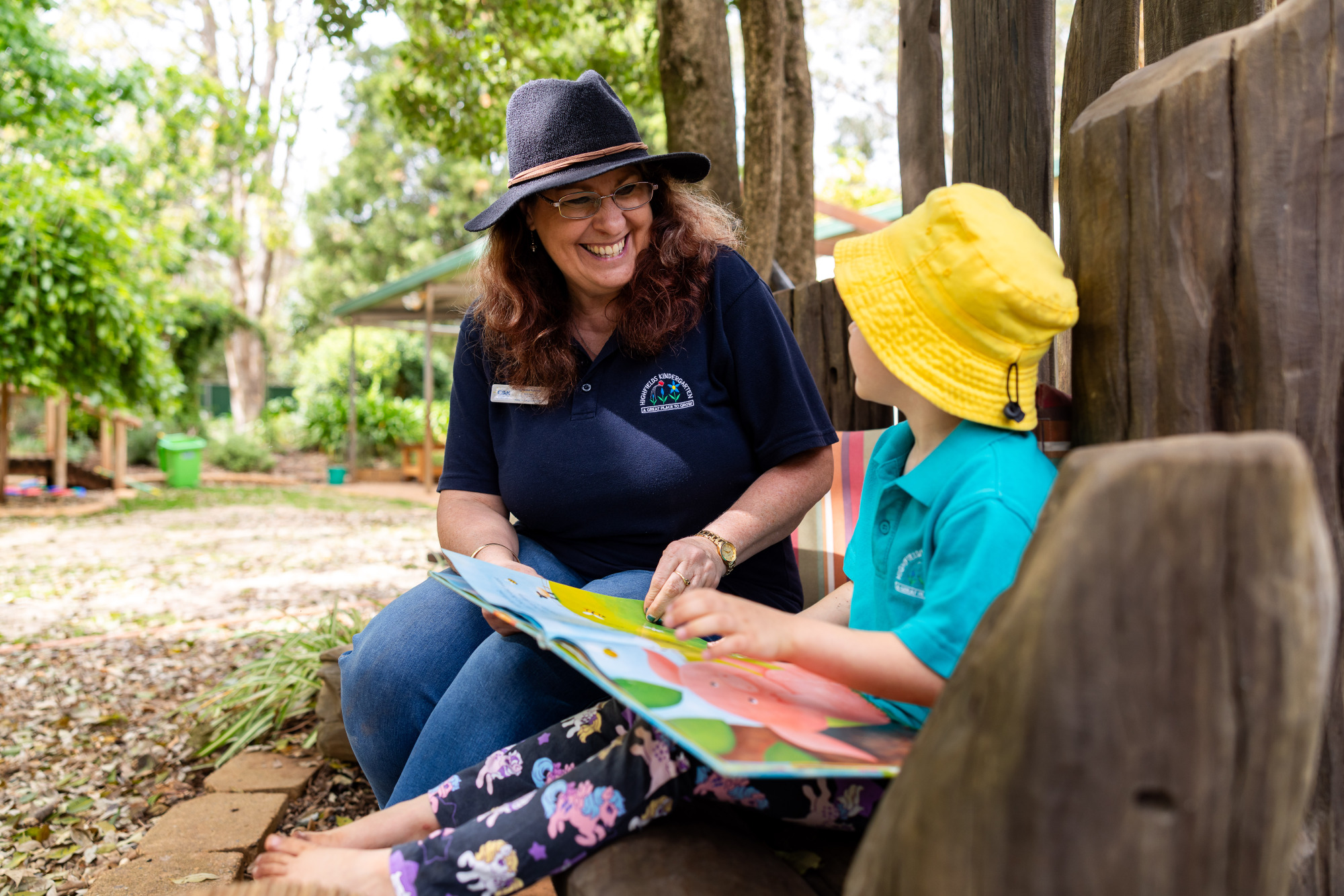Highfields & District Kindergarten - educator and child reading outdoors