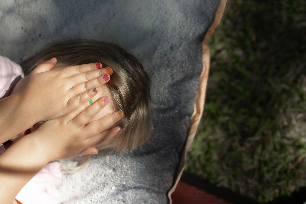 C&K Florence - child lying on a rug, covering her face