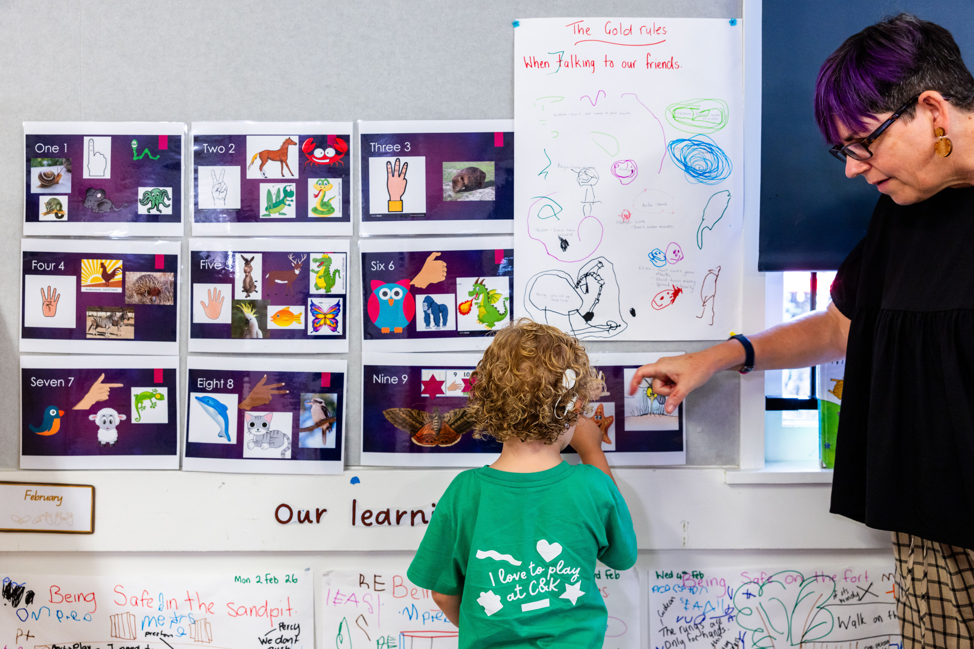 C&K Indooroopilly - educator signing to a deaf child as the read numbers on the wall in the classroom