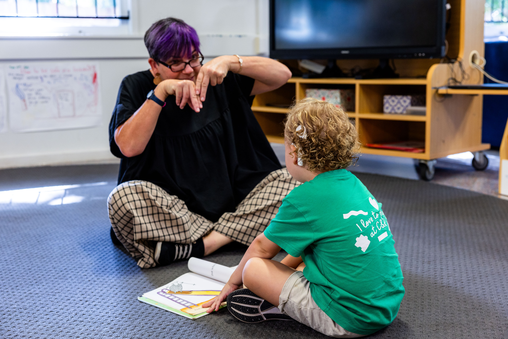 C&K Indooroopilly - educator signing to a deaf child, reading a book
