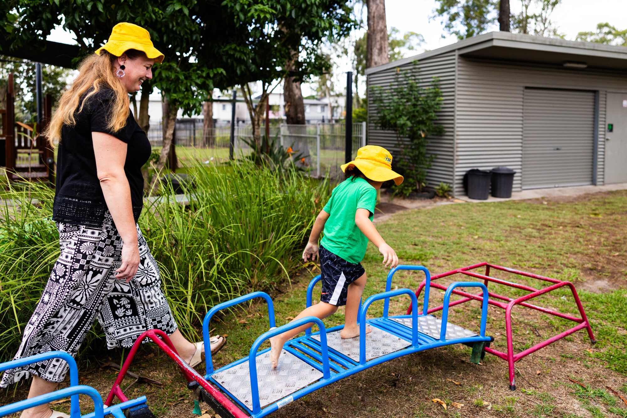 C&K Kruger - educator walking alongside a child on an obstacle course