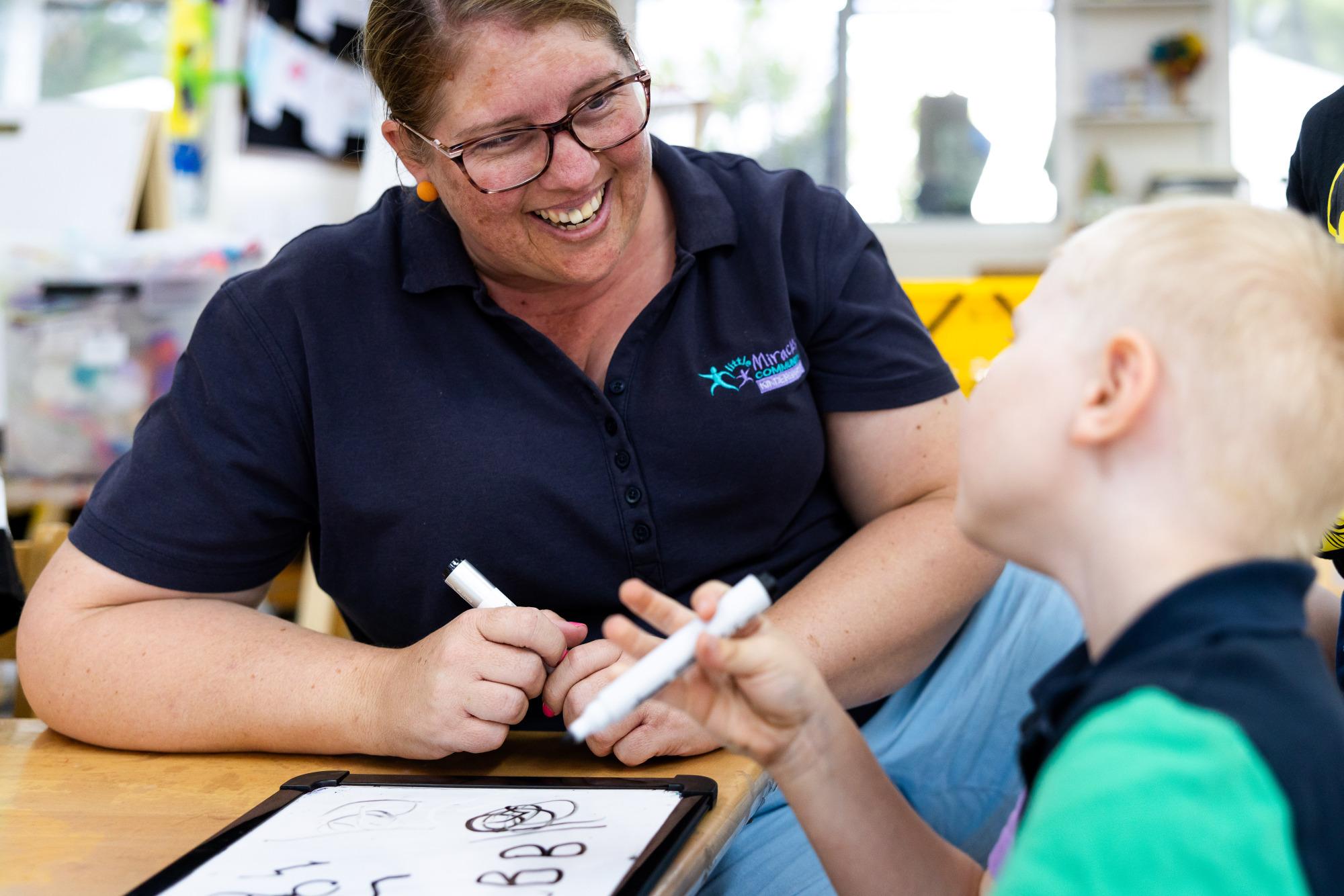 Little Miracles - educator and child writing