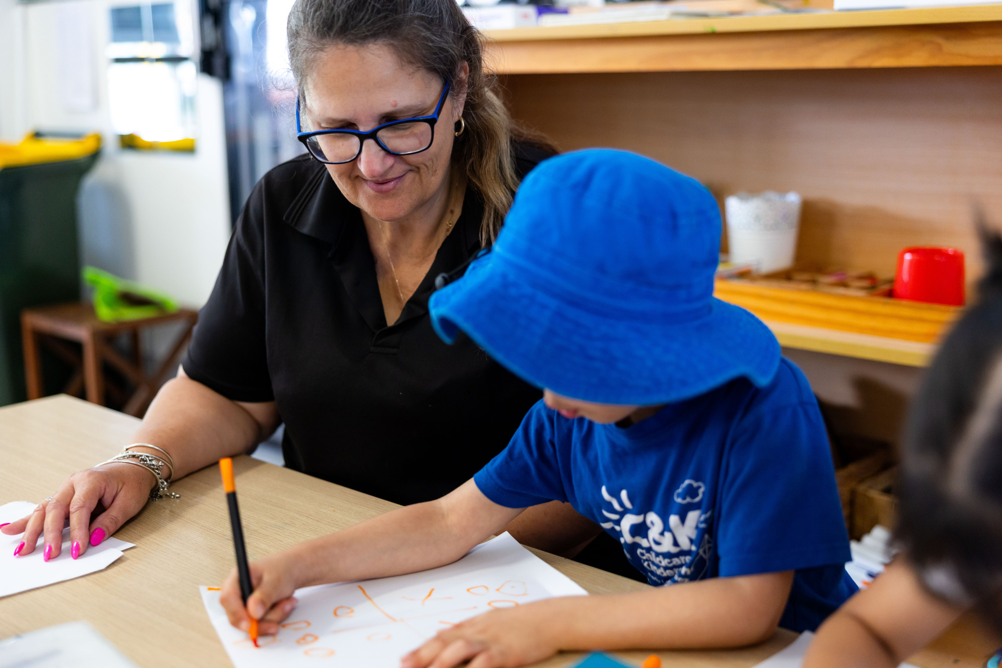 C&K Mt Gravatt East - educator with a child writing