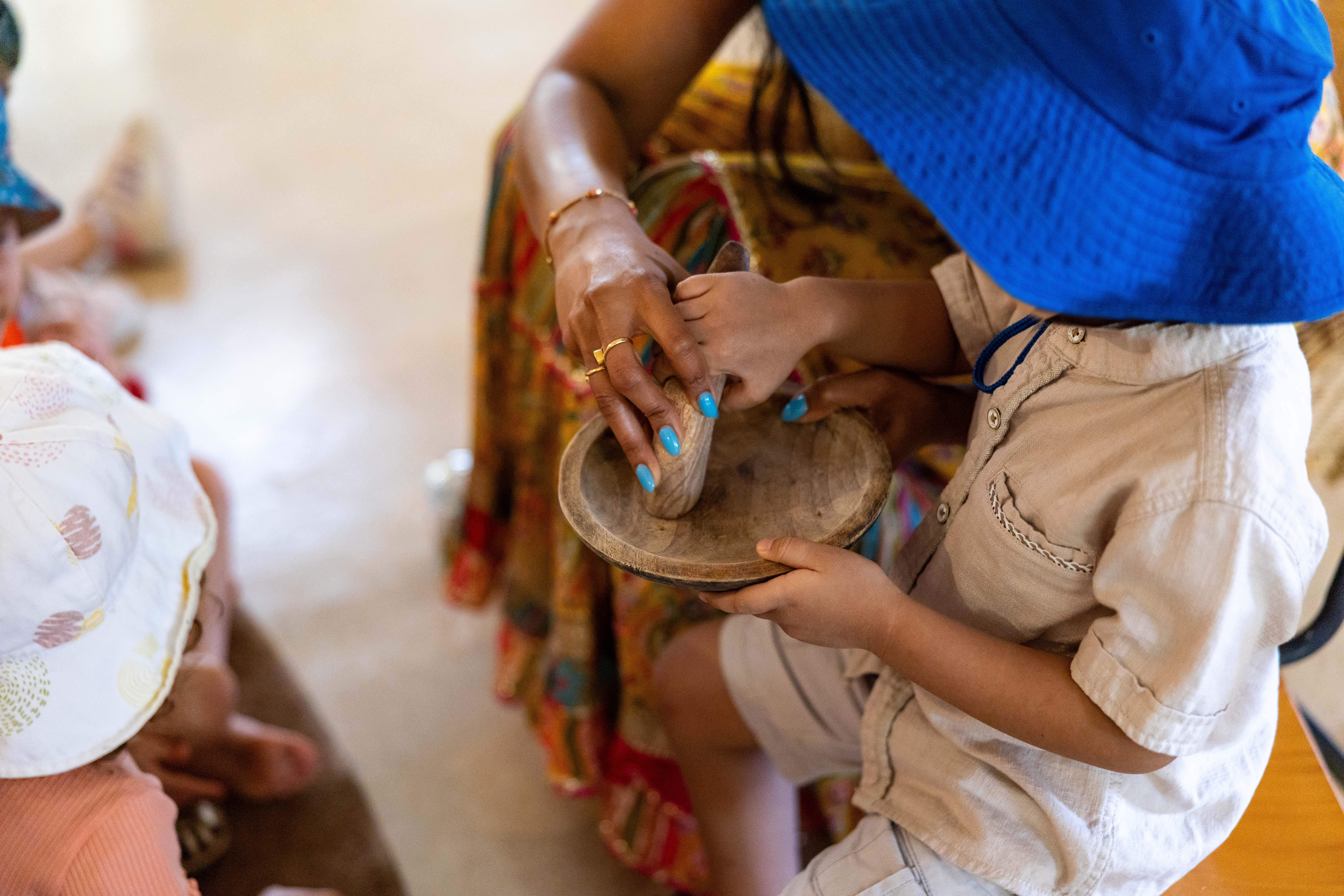 C&K Paddington - educator guiding a child's hand to use a wooden singing bowl
