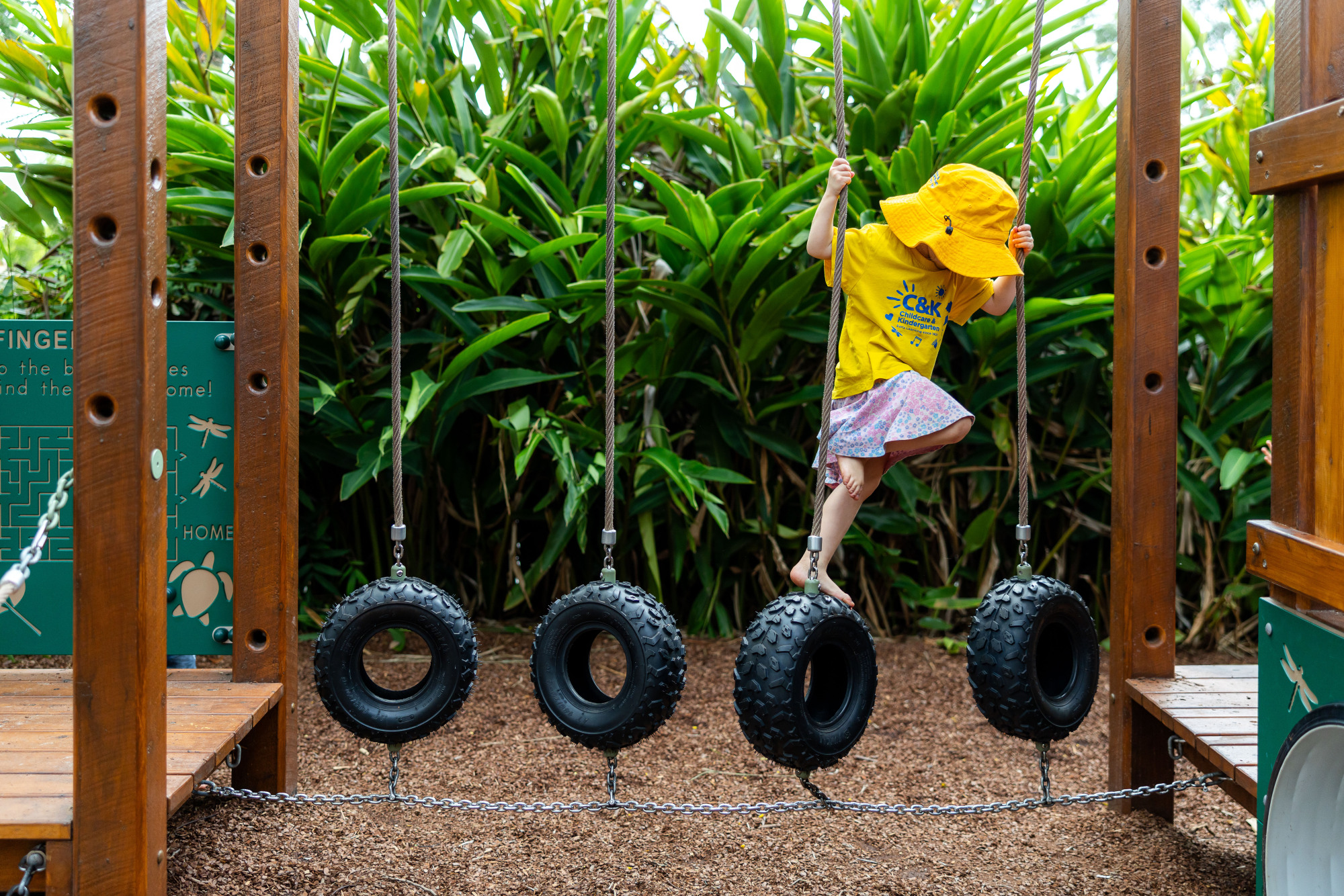 C&K Rosalie - child climbing across a hanging tyre bridge