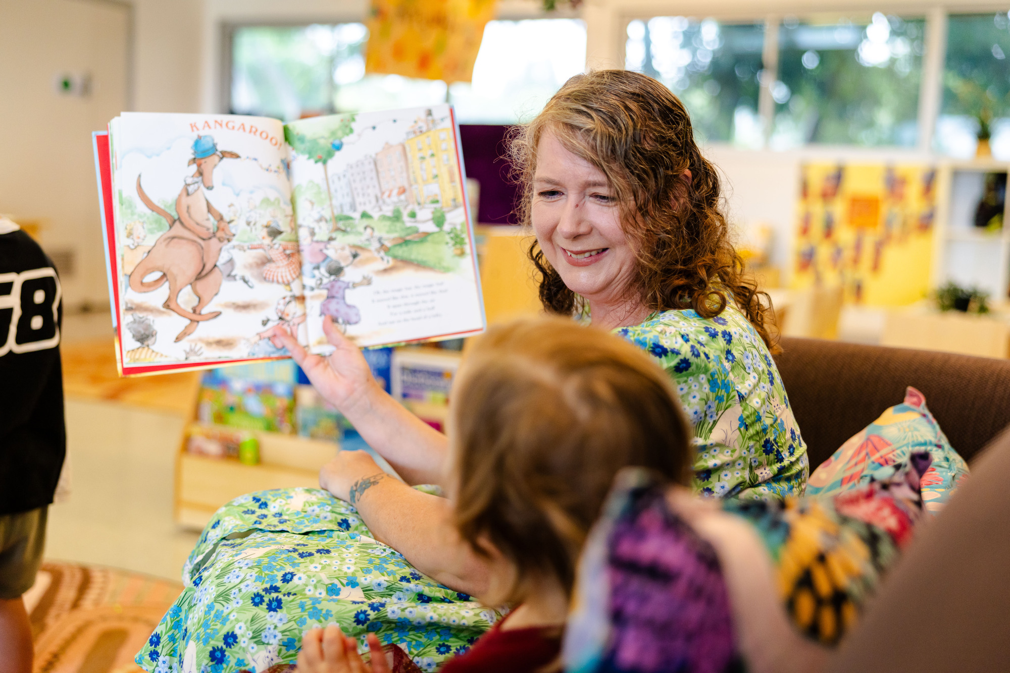 C&K Springfield Central - educator reading to a child on a couch indoors
