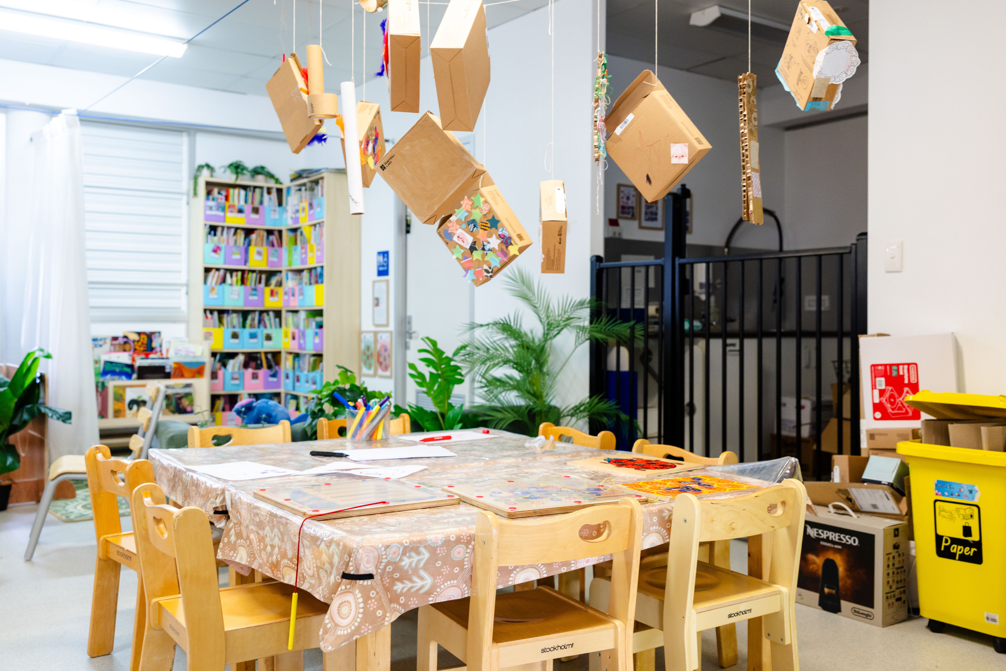 C&K Woodcrest - indoor classroom with artwork hanging from the ceiling and a shelves of children's books in the background