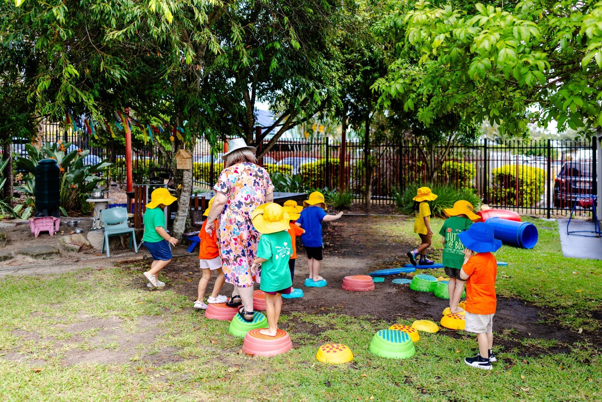 C&K Woodcrest - children and teacher playing on stepping stones in the outdoor space