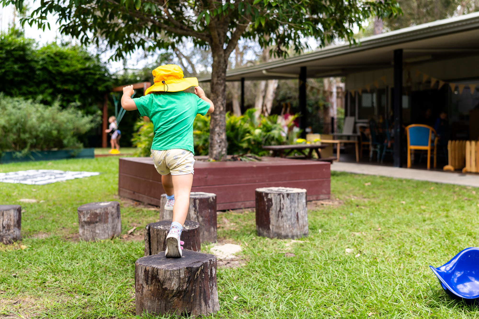 C&K Woodford - child running across wooden stumps