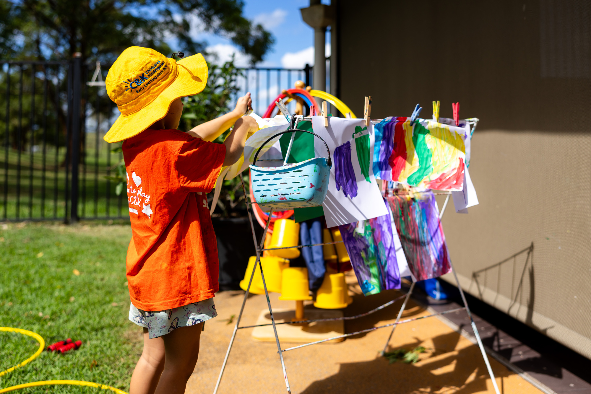 C&K Woodhill - child hanging up artwork to dry outside