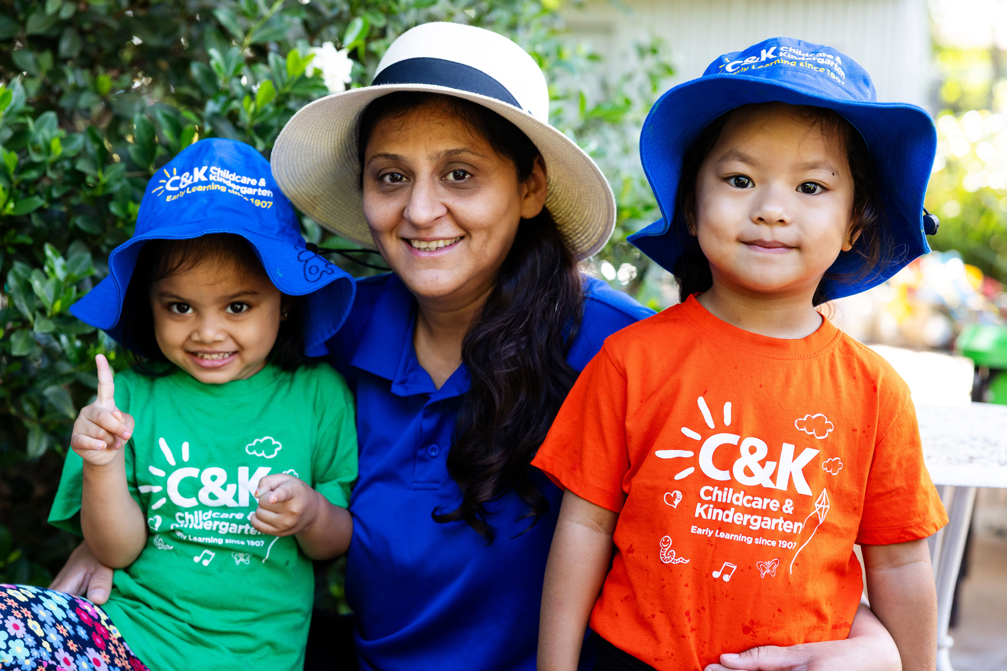 Educator and two kindy children outside in hats